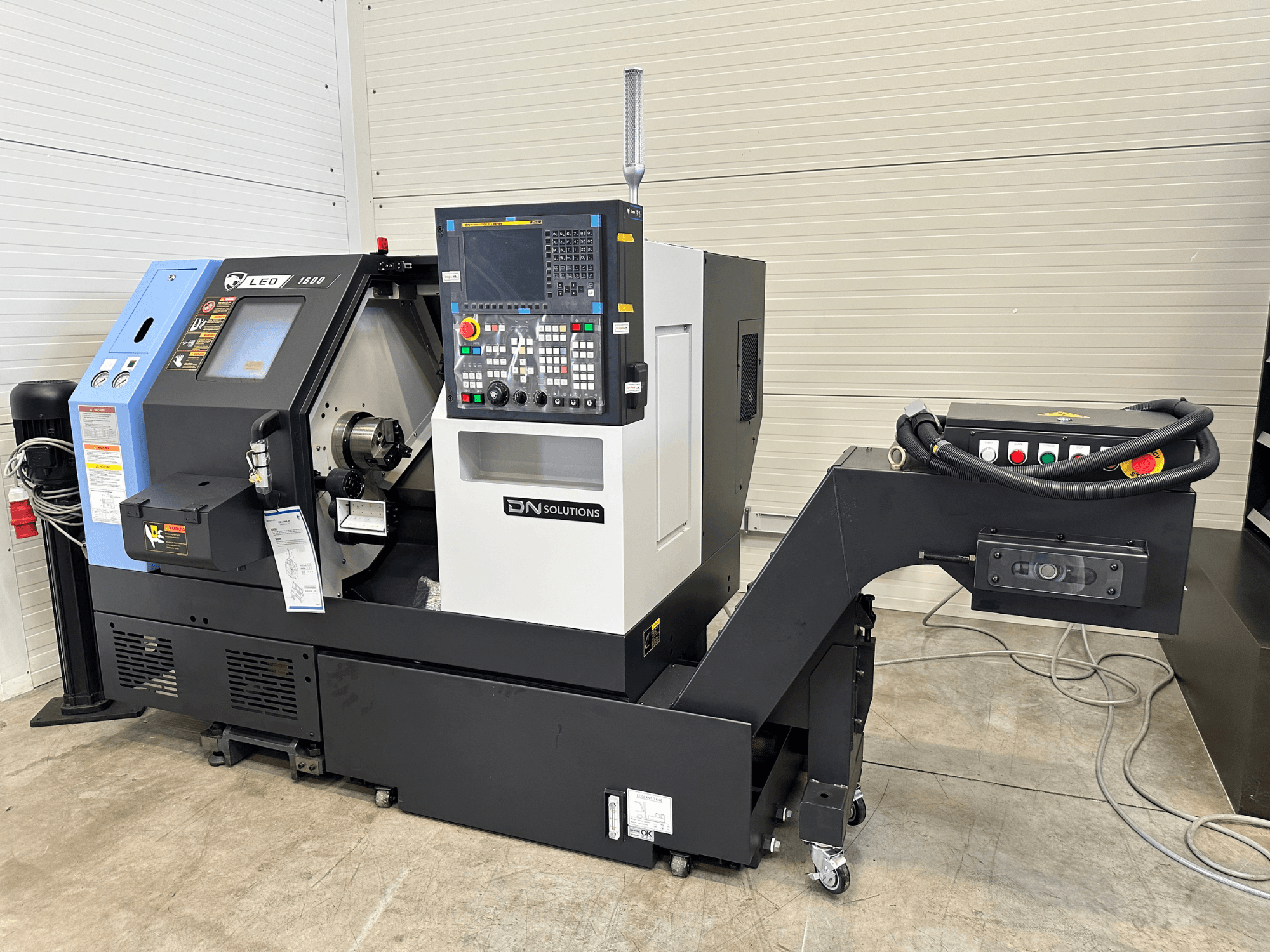 A DN SOLUTIONS Leo 1600 esztergaközpont előlapja, digitális vezérlőpanellel és szerszámtartóval, fekete alapon.
