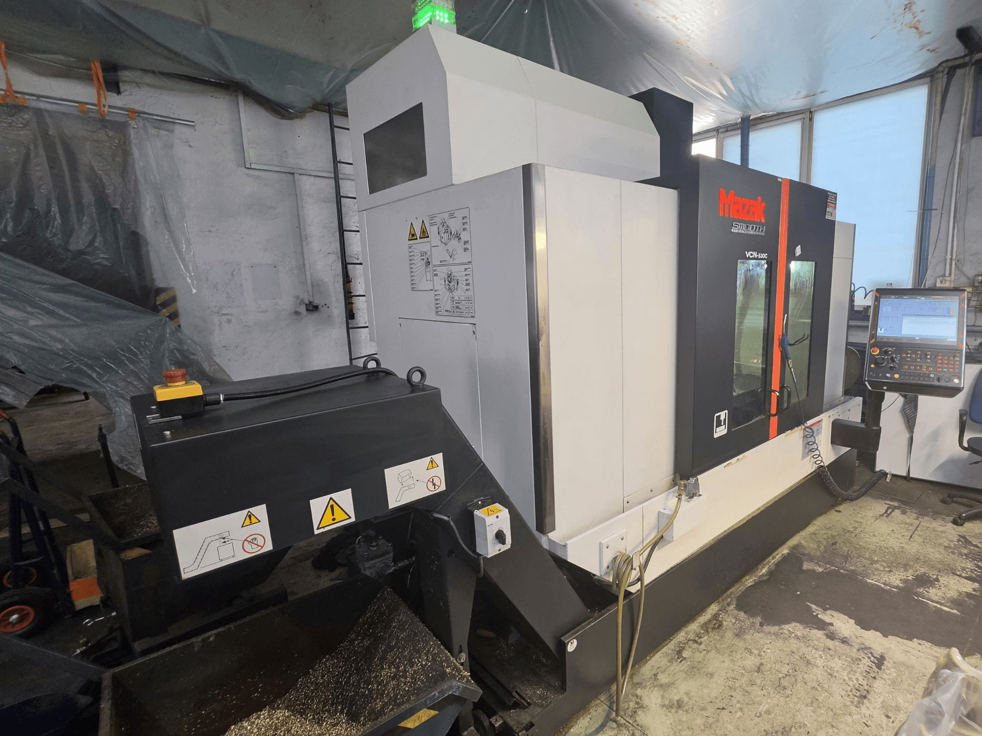 A Mazak VCN-530C függőleges megmunkálóközpont elölnézete, amelyen látható a vezérlőpanel, a szerszámlánc és a működési kijelzők.