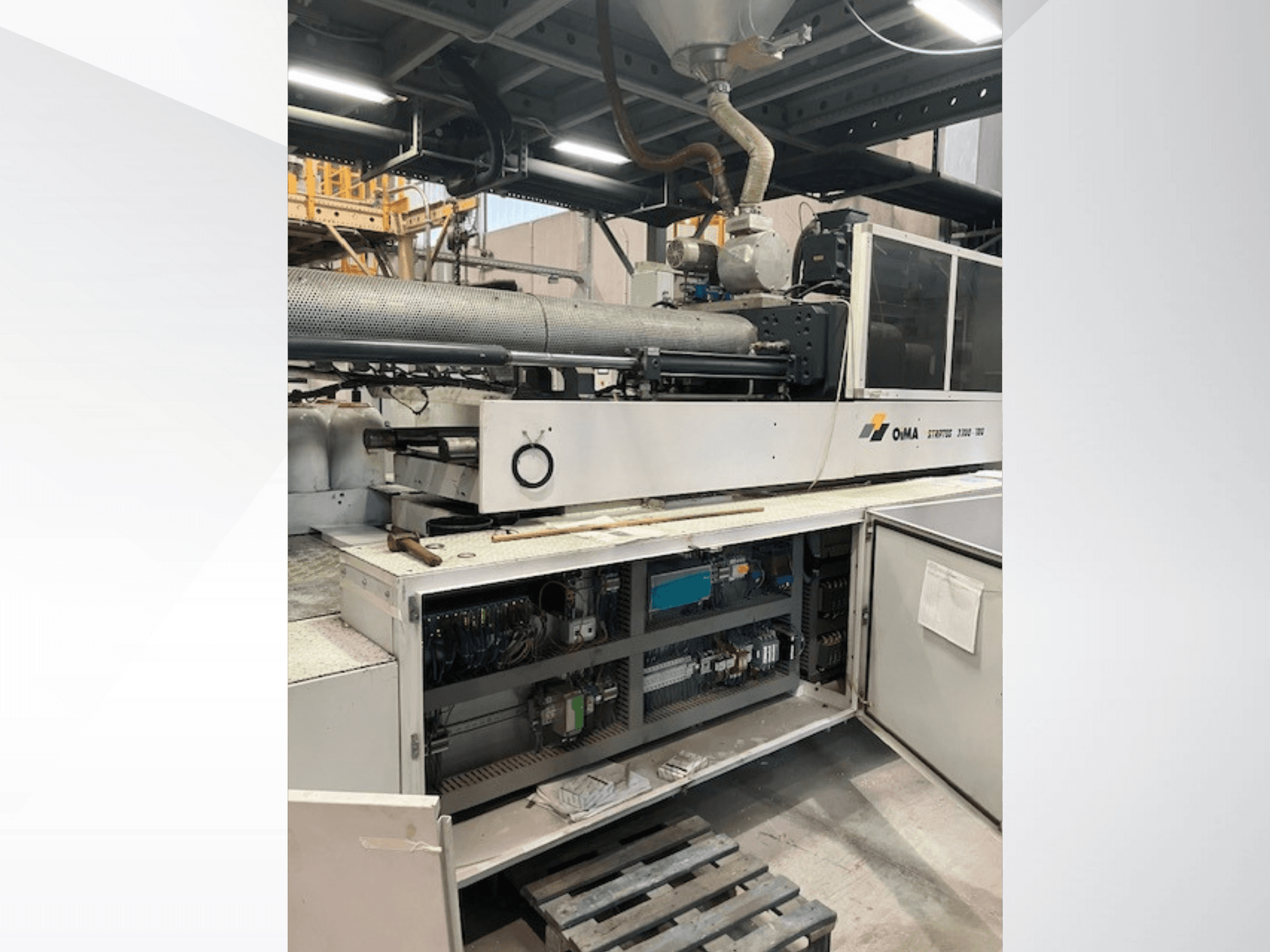 Az OMA 3500-as extruder elülső nézete, amely bemutatja a működő alkatrészeket, a vezérlőpanelt és a kábelezés részleteit. Nehézgépek ipari környezetben.