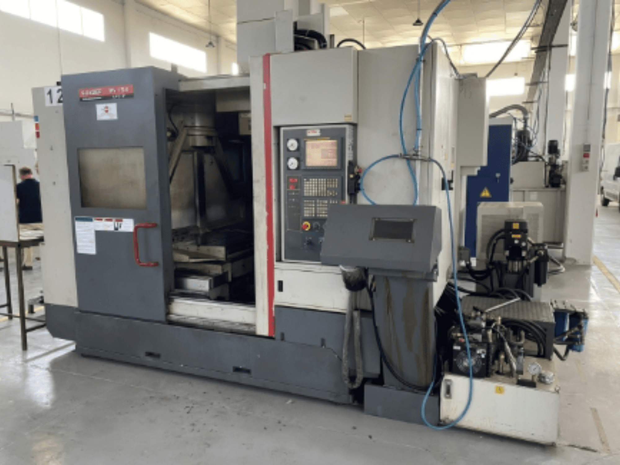 Quaser MV154APC-912 függőleges megmunkálóközpont, elölnézetben a vezérlőpanel, a nyitott ajtó és a gép alkatrészei.