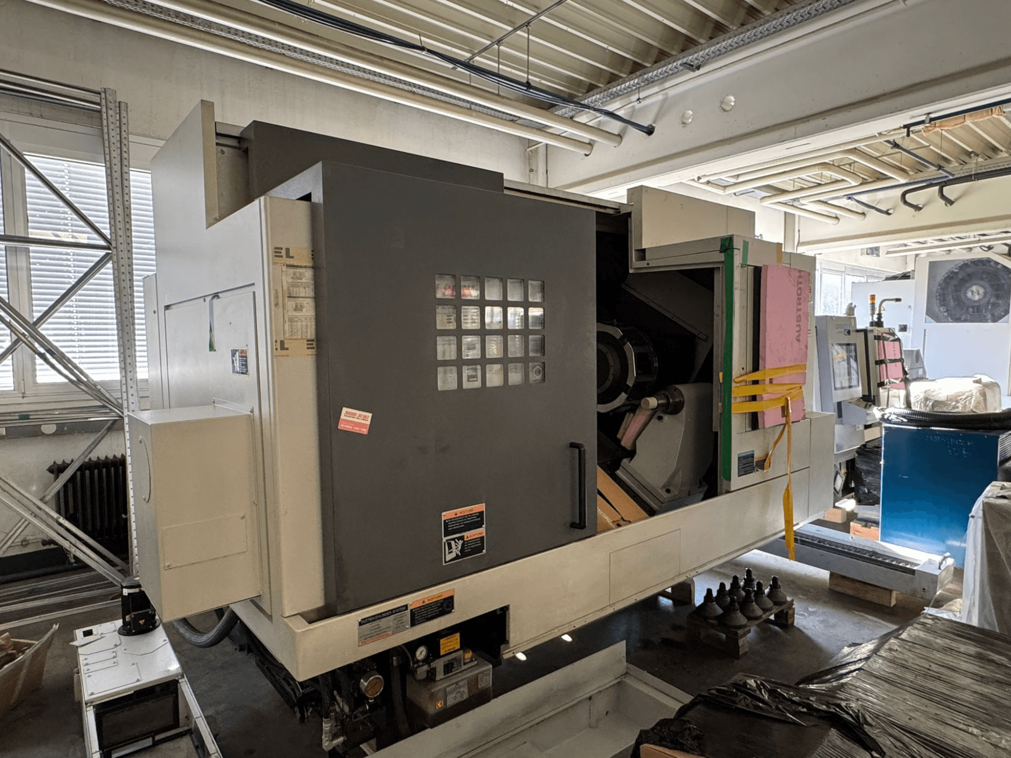 MORI SEIKI NL 3000 MC/700 vízszintes eszterga, elölnézet a vezérlőpanellel, a tárolóterülettel és a védőburkolattal.