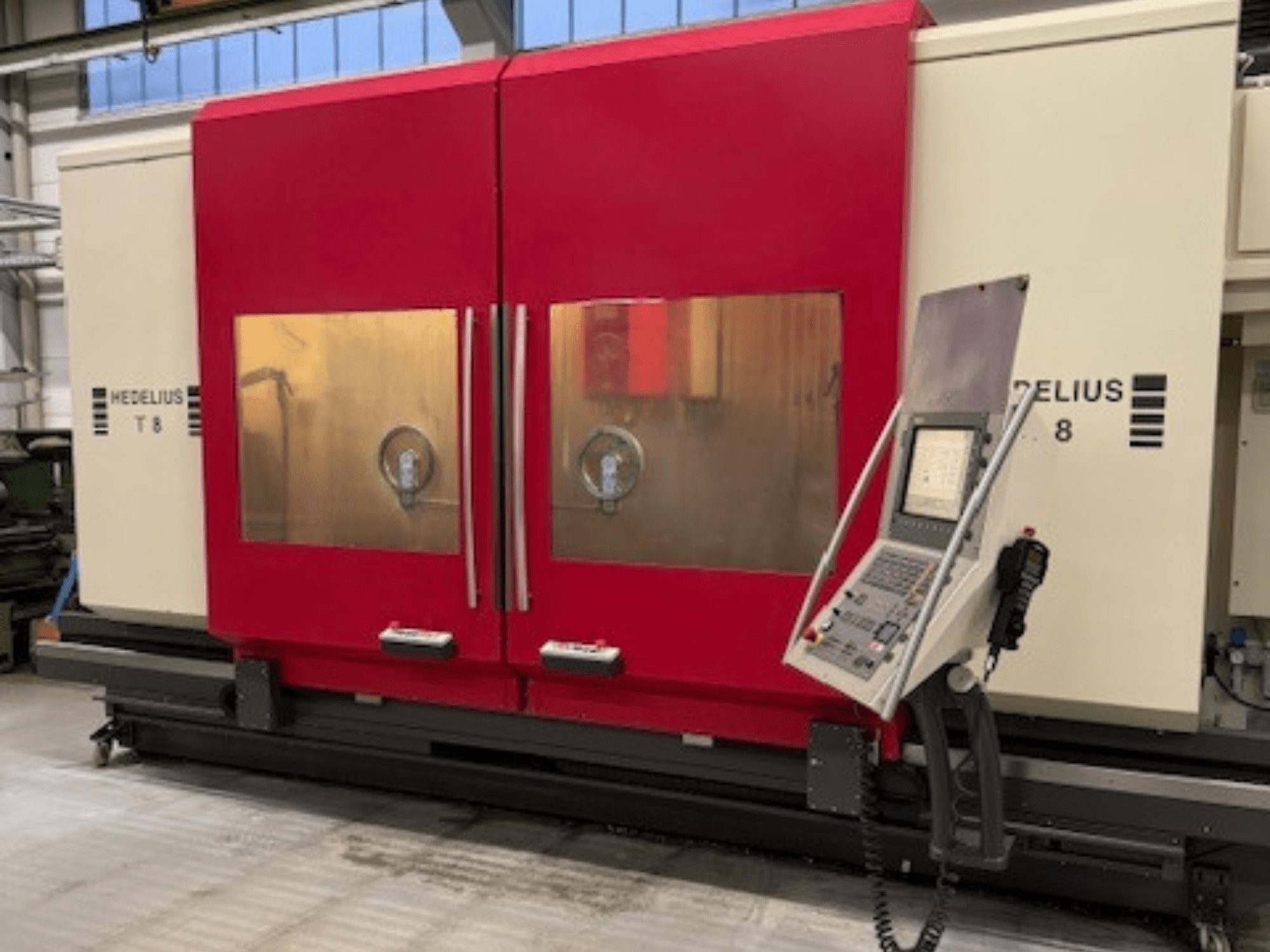 HEDELIUS T8 CNC-gép elölnézetben, piros ajtókkal, vezérlőpanellel és a belső alkatrészek láthatóságával.