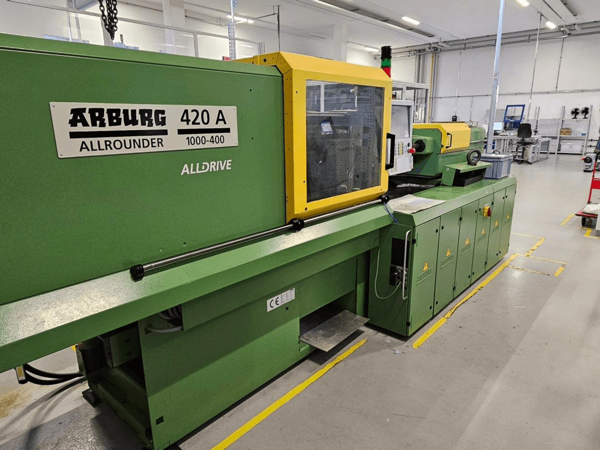 ARBURG 420 A Allrounder 1000-400, elölnézet; zöld gép sárga panellel, érintőképernyővel és biztonsági funkciókkal.