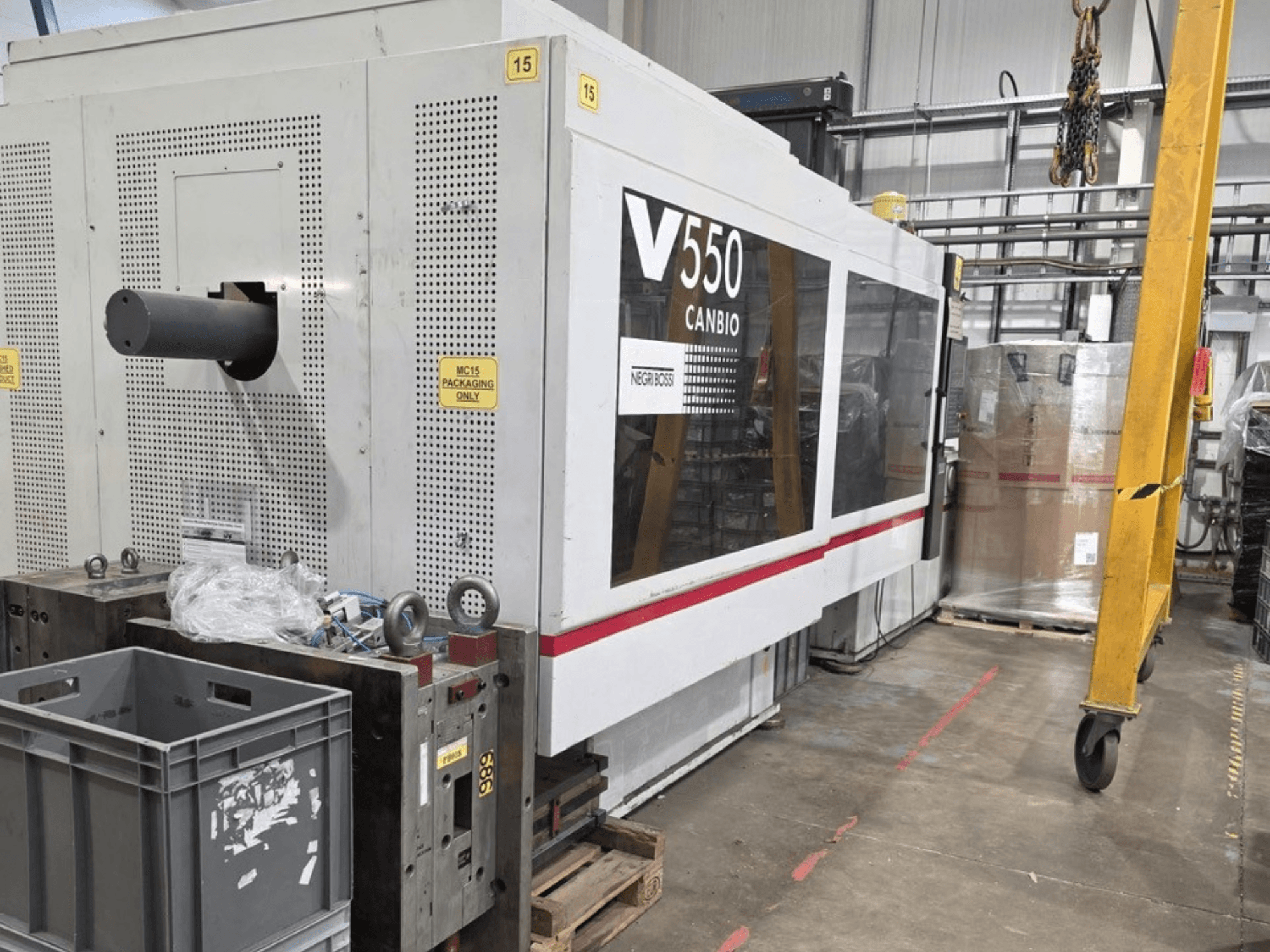 Negri Bossi V55000H-4250 hidraulikus fröccsöntőgép, oldalnézet, előtérben a vezérlőpanel és a szürke ládák.