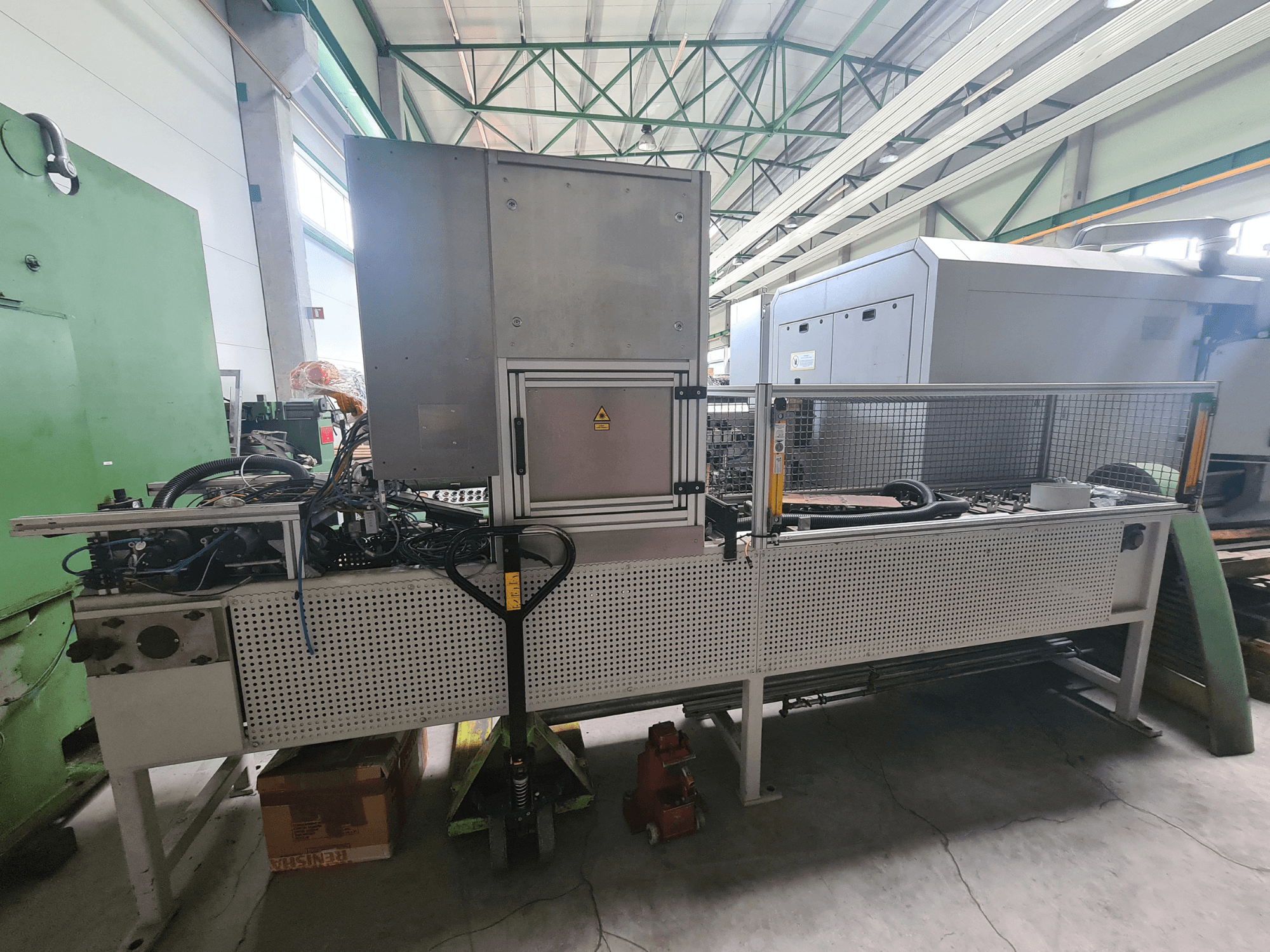 Ipari gépek fémkerettel, tömlőkkel és vezérlőpanellel, oldalról nézve, gyári környezetben.