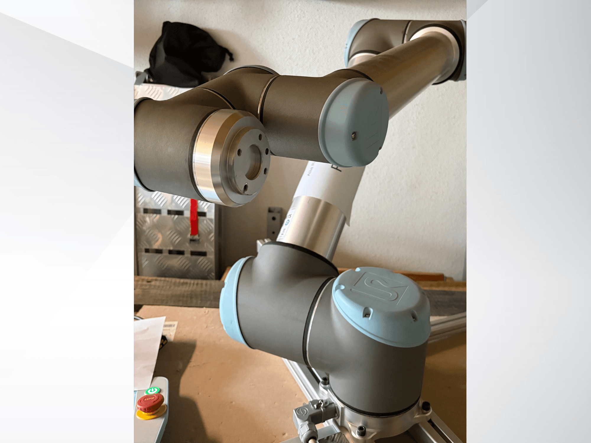Az Universal Robots UR10 robotkar oldalnézetben, kiemelve az ízületeket és a szürkéskék dizájnelemeket.