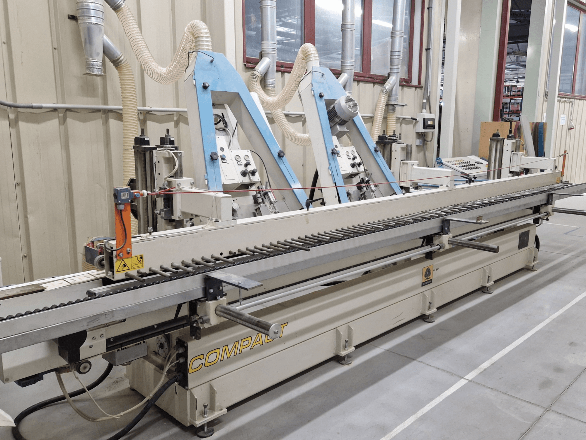 Szalagcsiszoló TECNOLEGNO COMPACT 52 egy műhelyben, a kezelőpanel és a csiszolószalag mechanizmusa oldalnézetből.