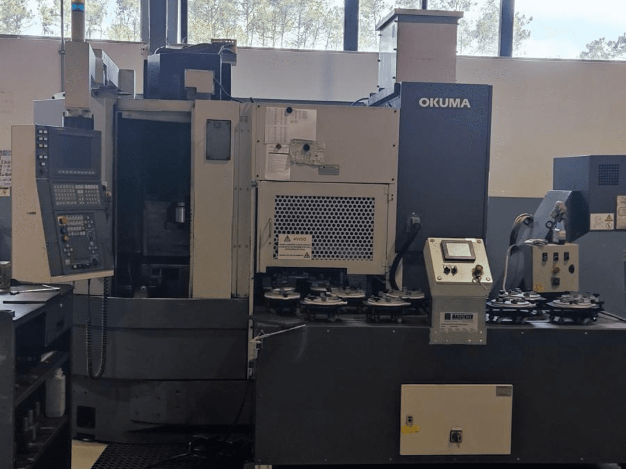 Okuma LVT300 függőleges esztergagép elölnézetben, a vezérlőpanel, a szerszámtartók és a megmunkálási terület.