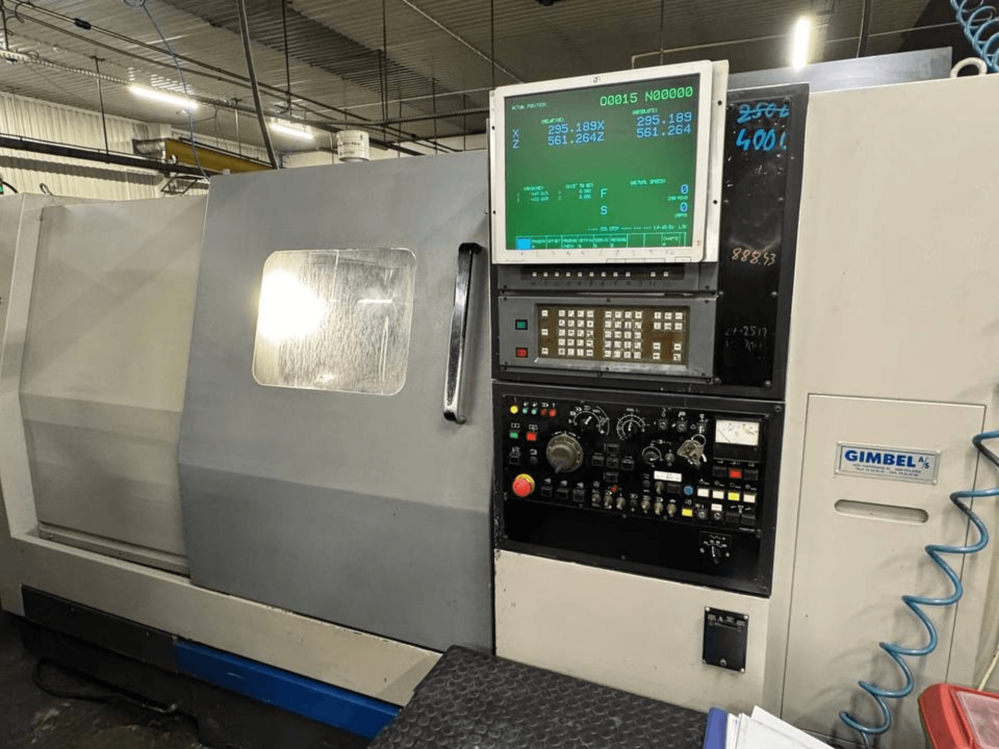 A Takisawa TS-35 vízszintes esztergagép elülső nézete, digitális kijelzővel és kezelőszervekkel ellátott kezelőpanellel.