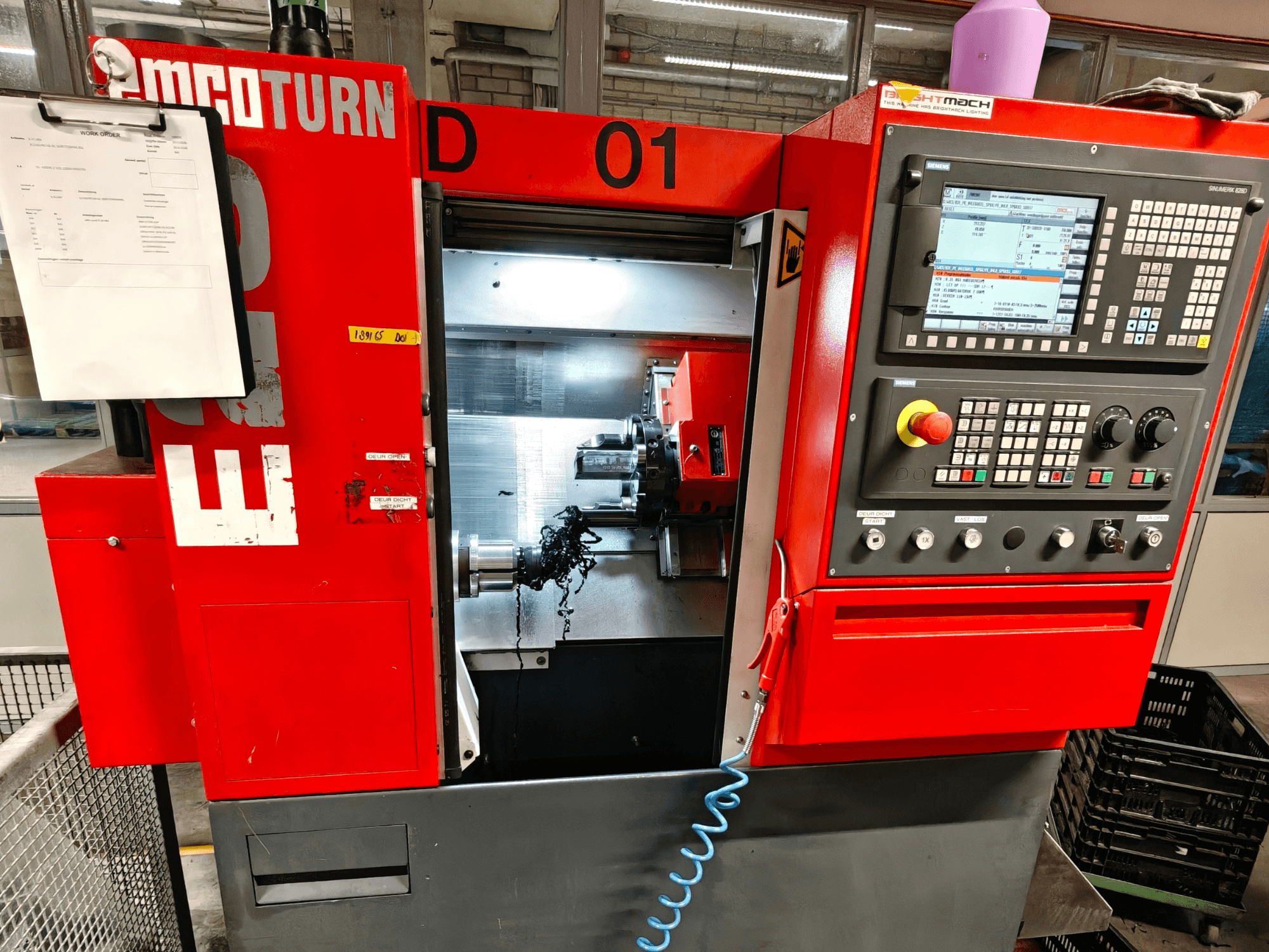 Az EMCO TURN E25 vízszintes esztergagép elülső nézete, a kezelőszervekkel, a szerszámtartóval és a forgáccsal ellátott munkaterülettel.