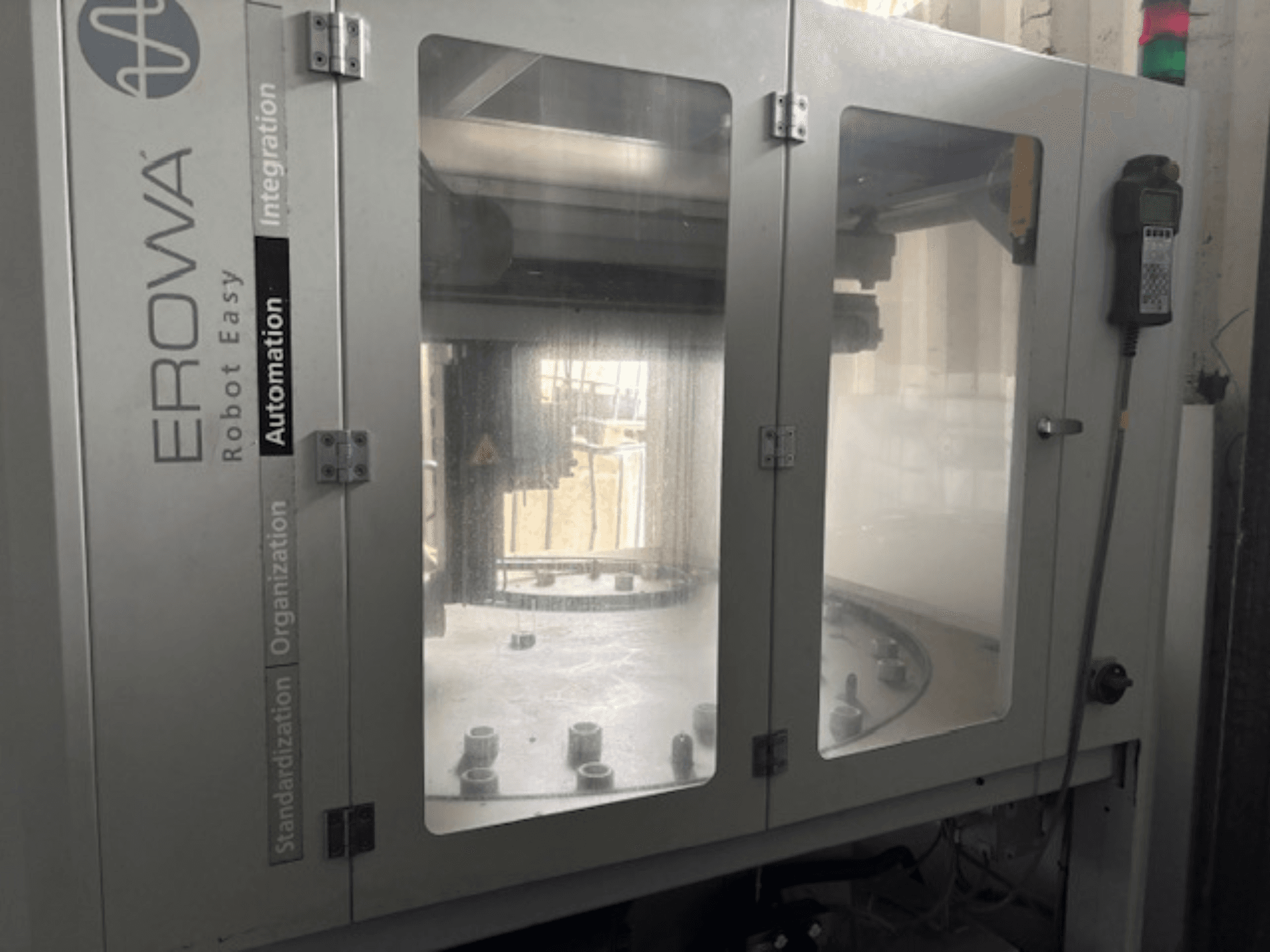 Az EROWA Robot Easy Automation elülső nézete; átlátszó ajtók, látható automatizálási alkatrészek és vezérlőpanel.