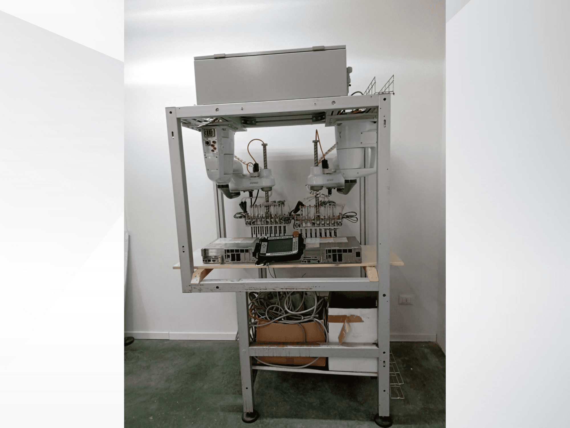 Automatizált robotizált munkaállomás két karral, kijelzőegységgel és elektronikával fémkereten, elölnézet, fejlett technológiai beállítás.