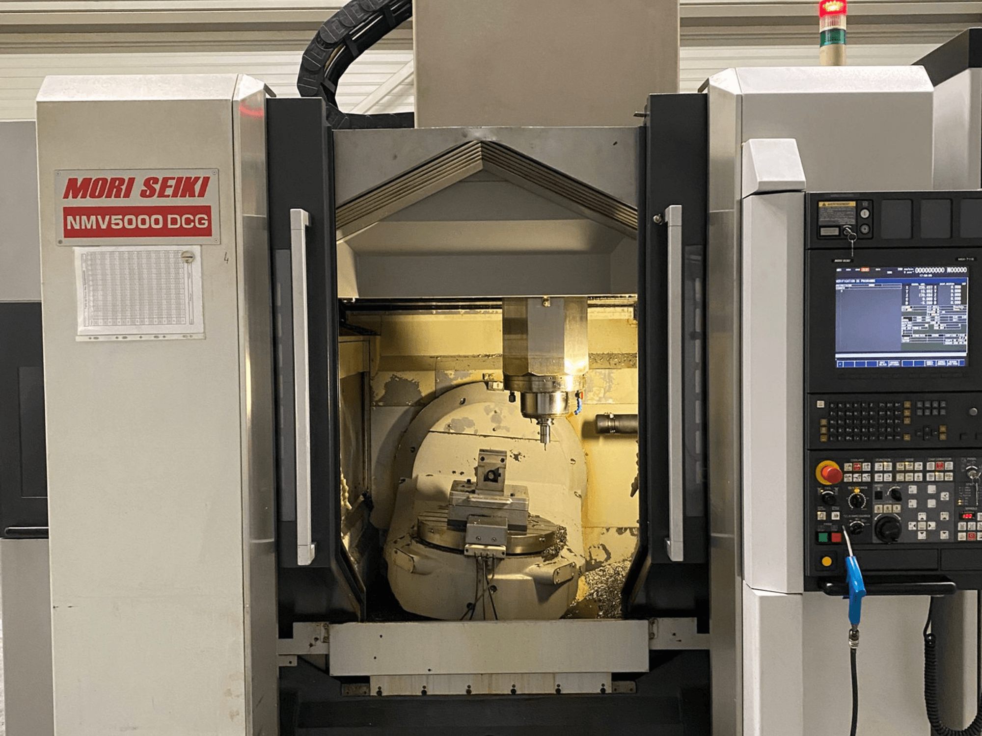 MORI SEIKI NMV 5000DCG univerzális megmunkálóközpont, elölnézetben a vezérlőpanel és a belső megmunkálási terület.