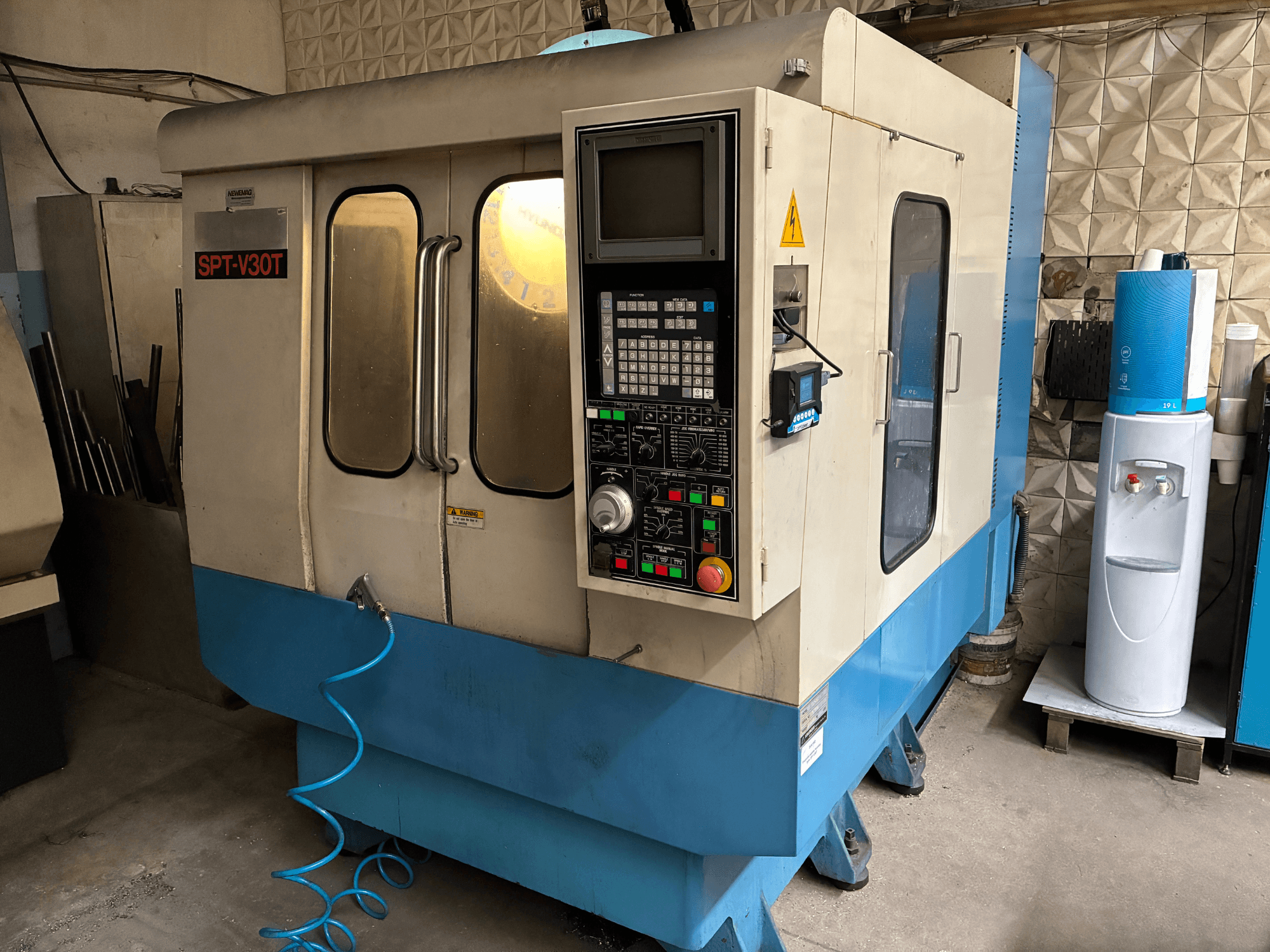 SPT-V30T CNC gép kék-fehérben, elölnézetben a vezérlőpanel, az ajtók és a légtömlő. Tökéletes precíziós megmunkáláshoz.
