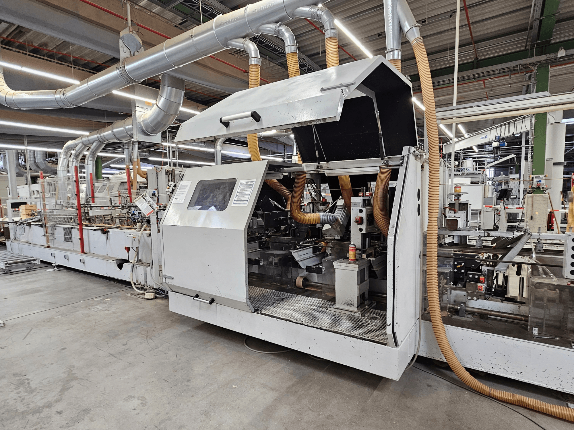 HOMAG FG63 élfűrészgép gyári környezetben, oldalnézetben a működő alkatrészek és a porelszívó rendszer látható.