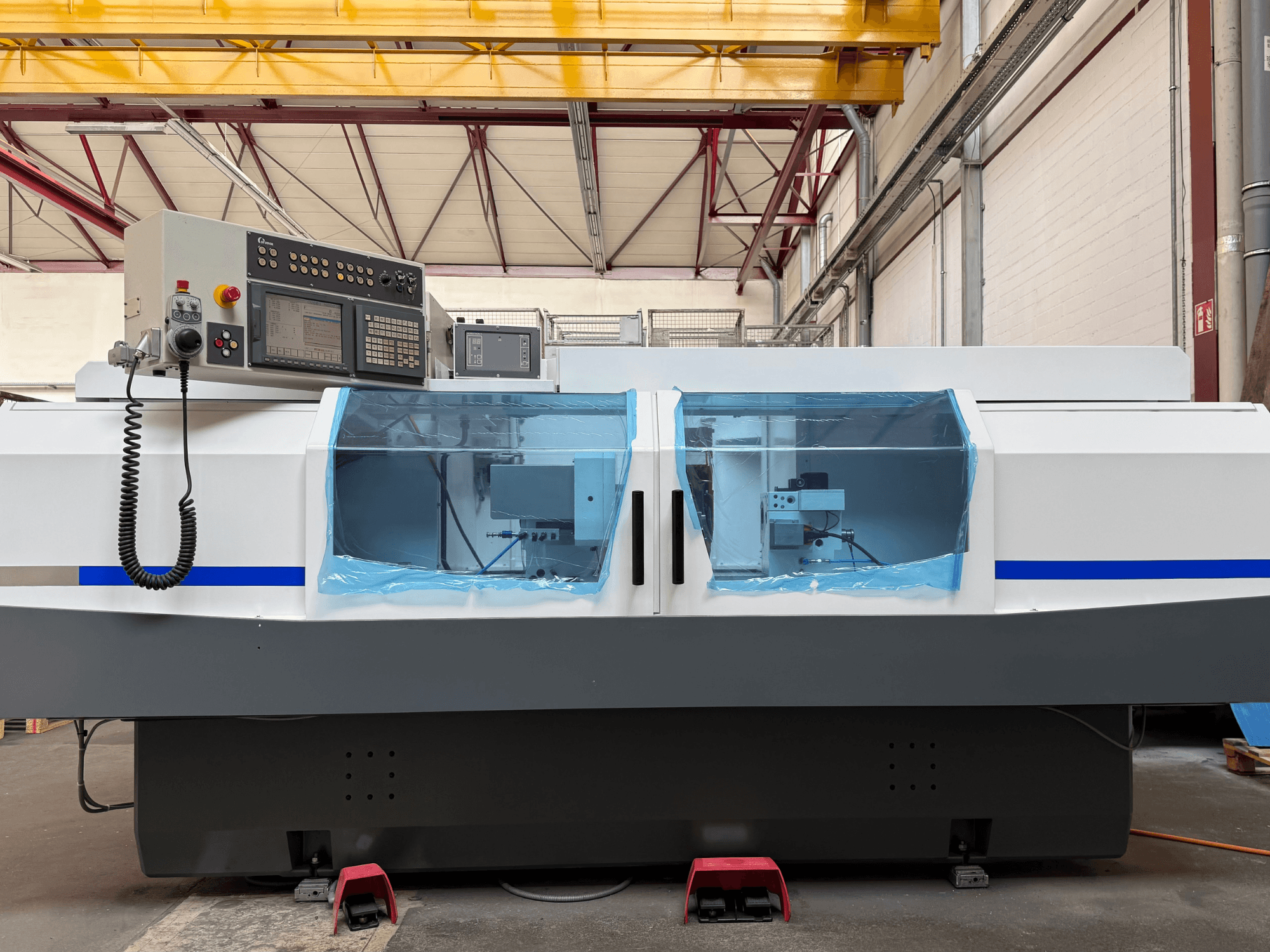 A STUDER S33 CNC hengeres köszörűgép oldalnézete, a kezelőpanellel és az átlátszó biztonsági burkolatokkal.