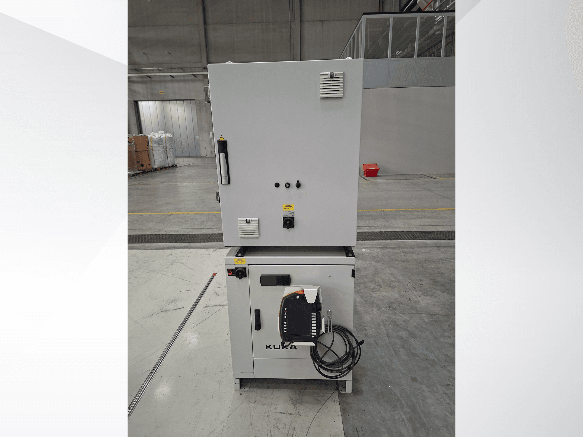 KUKA KR 90 R2700 PRO C4 FLR robotkar-vezérlő, elölnézet, amelyen látható a vezérlőpanel és a biztonsági címkék egy tágas raktárban.