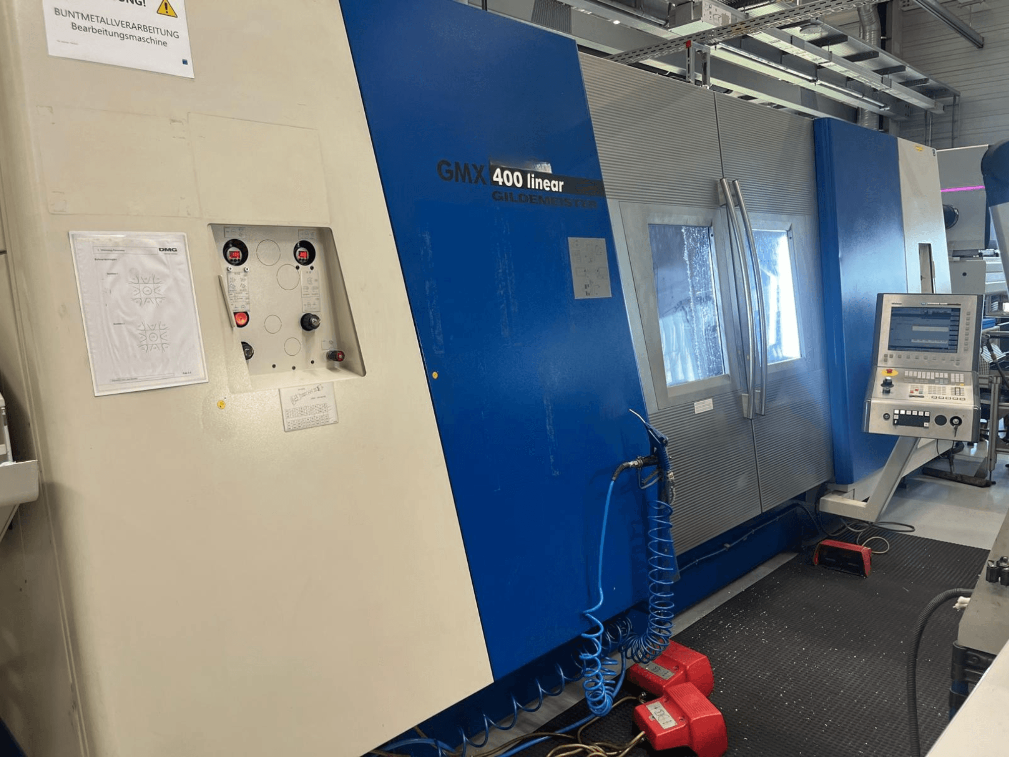 Gildemeister GMX 400 lineáris eszterga-marógép, elölnézet, amelyen látható a vezérlőpanel, a hűtőfolyadék-rendszer és a működtető gombok.