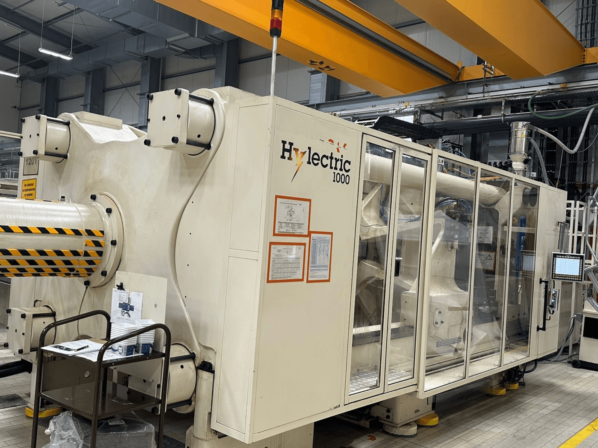 Husky Hylelectric H1000 RS95/80 elektromos fröccsöntőgép, oldalnézet, amelyen látható a vezérlőpanel és a biztonsági berendezések.