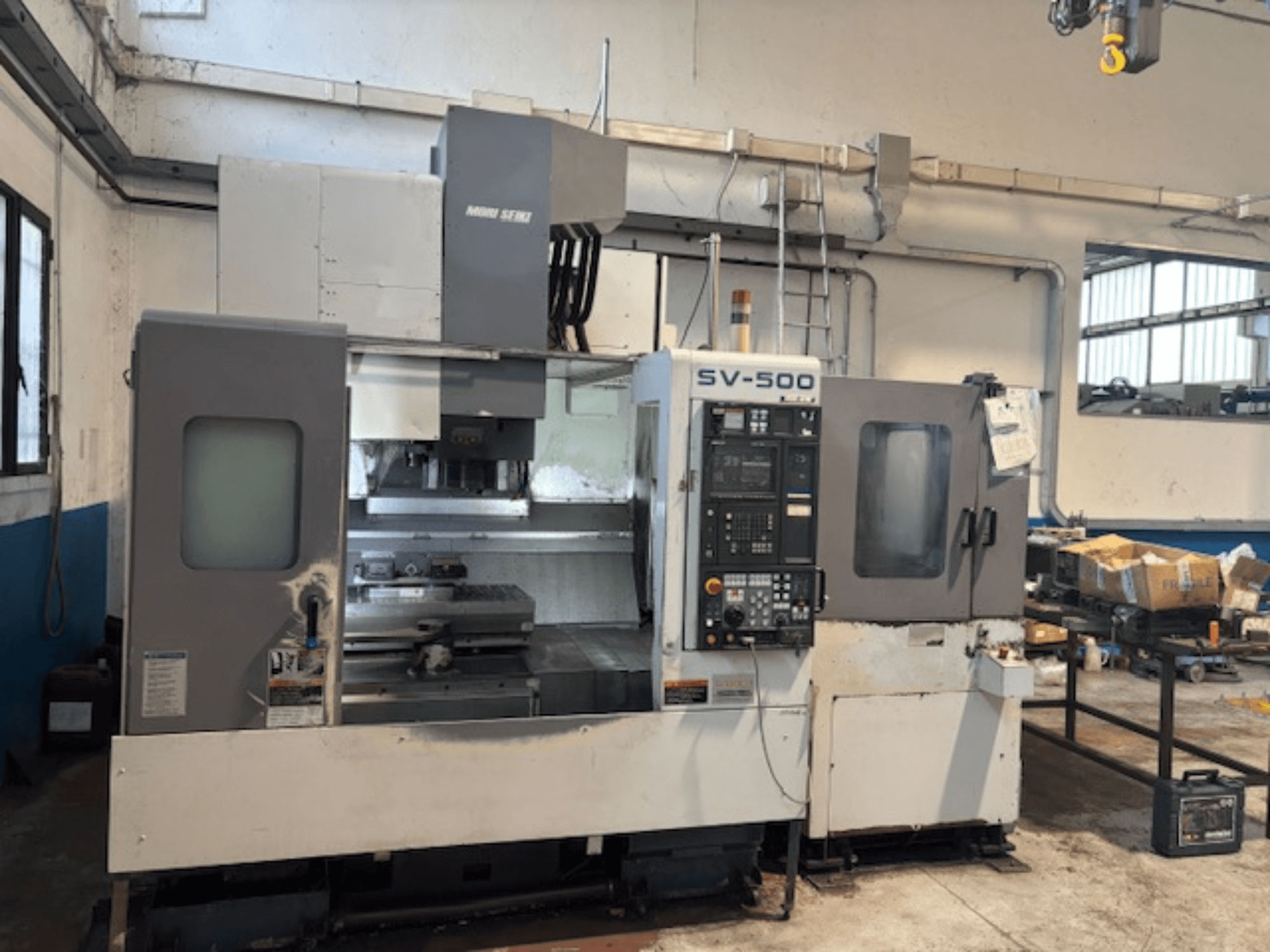 MORI SEIKI SV-500/40 függőleges megmunkálóközpont egy műhelyben, elölnézetben a vezérlőpanel és a megmunkálási terület.