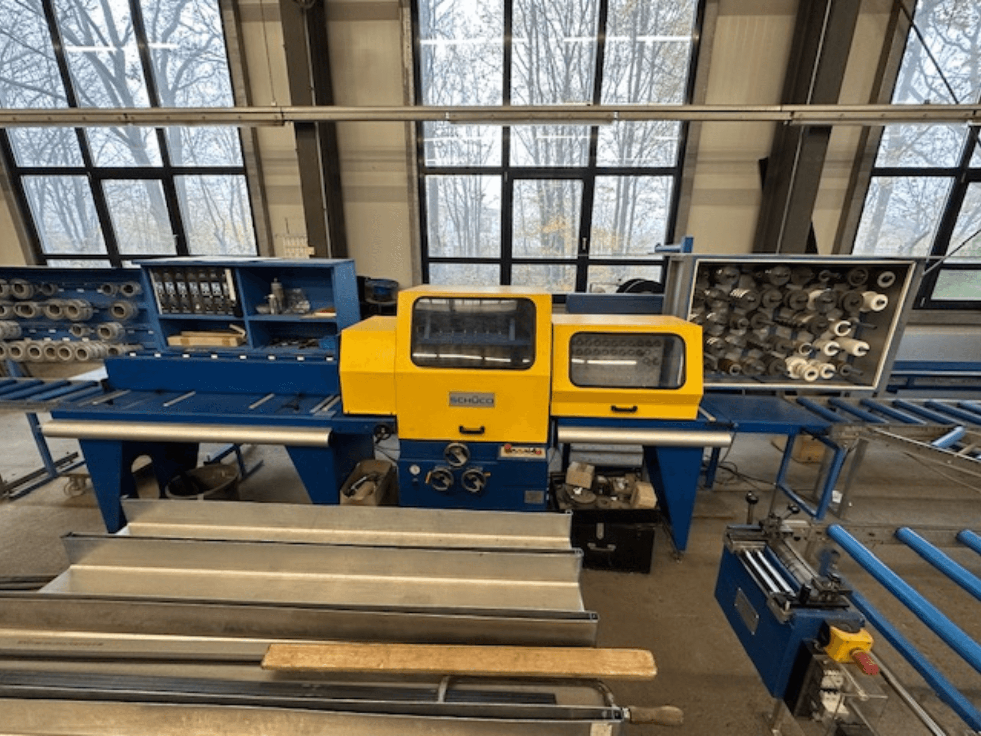 A SCHÜCO ISOMAT 4 szerszámgép előlapja, sárga vezérlőpanellel, több tekerccsel és tárolórekesszel.