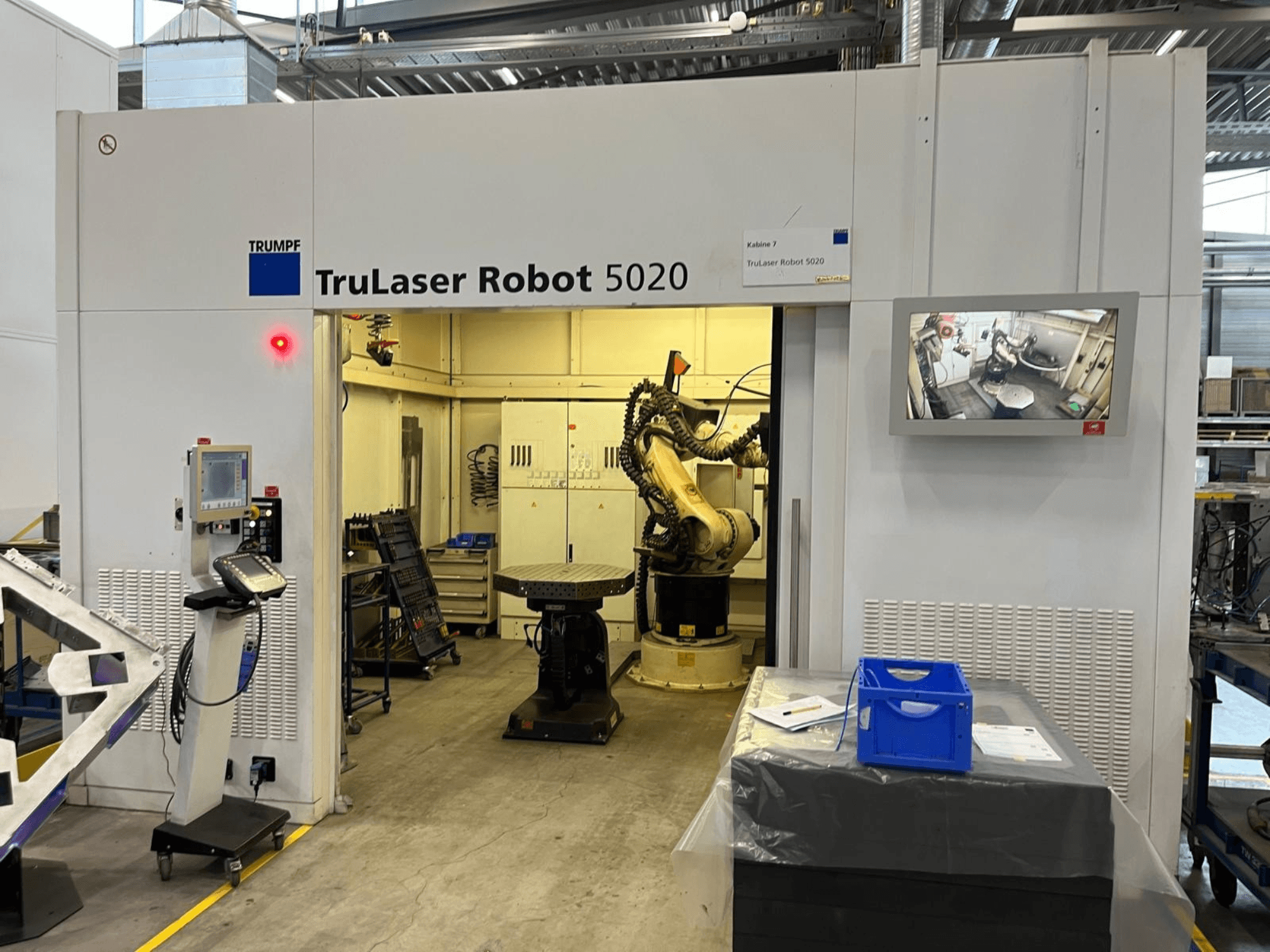 A TRUMPF TruLaser Robot 5020 ipari környezetben, a vezérlőelemekkel, a robotkarral és a műveleteket megjelenítő monitorral.