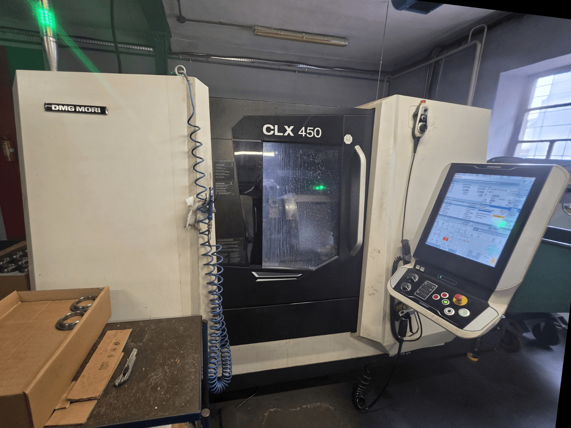 A DMG MORI CLX 450 V3 vízszintes eszterga elölnézete, amelyen látható a vezérlőpanel, a hűtőfolyadék-rendszer és a munkaterület.