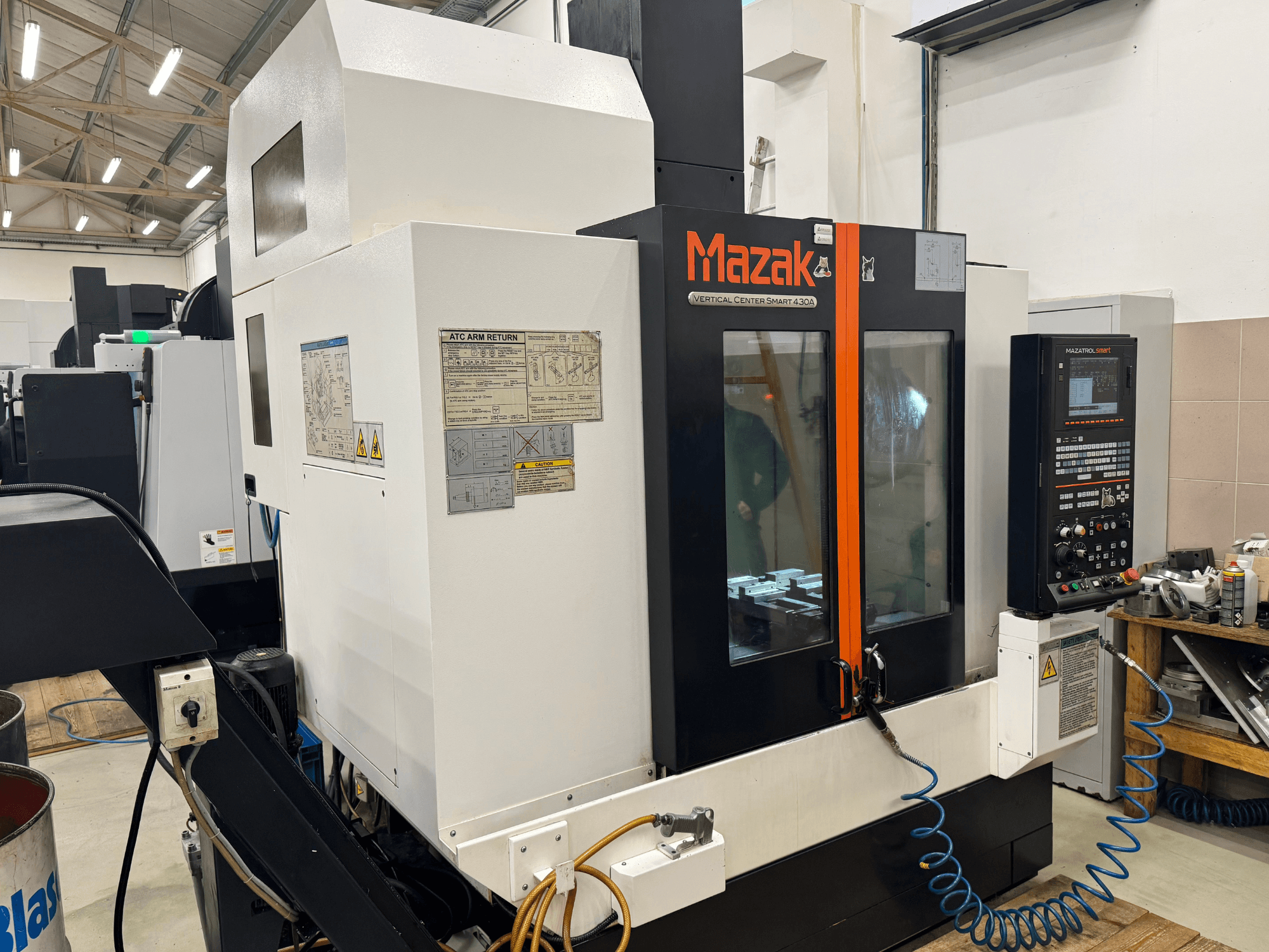 Mazak Vertical Center Smart 430A, előlnézet; CNC marógép, a vezérlőpanel, az átlátszó burkolat és a szerszámtartó látható.
