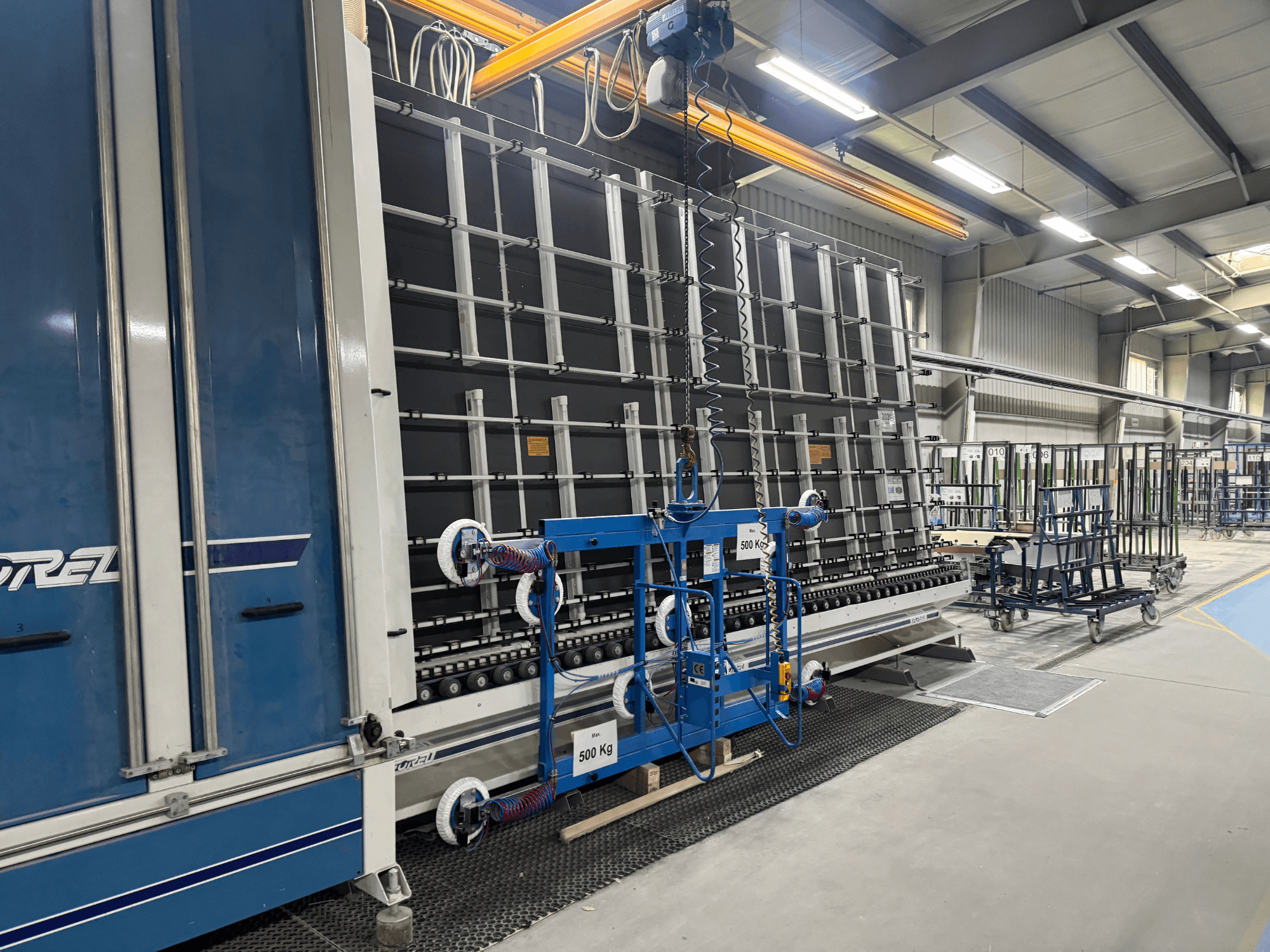 A Drel ipari berendezése, nagyméretű kerettel és emelőszerkezettel, oldalnézetből, gyári környezetben.