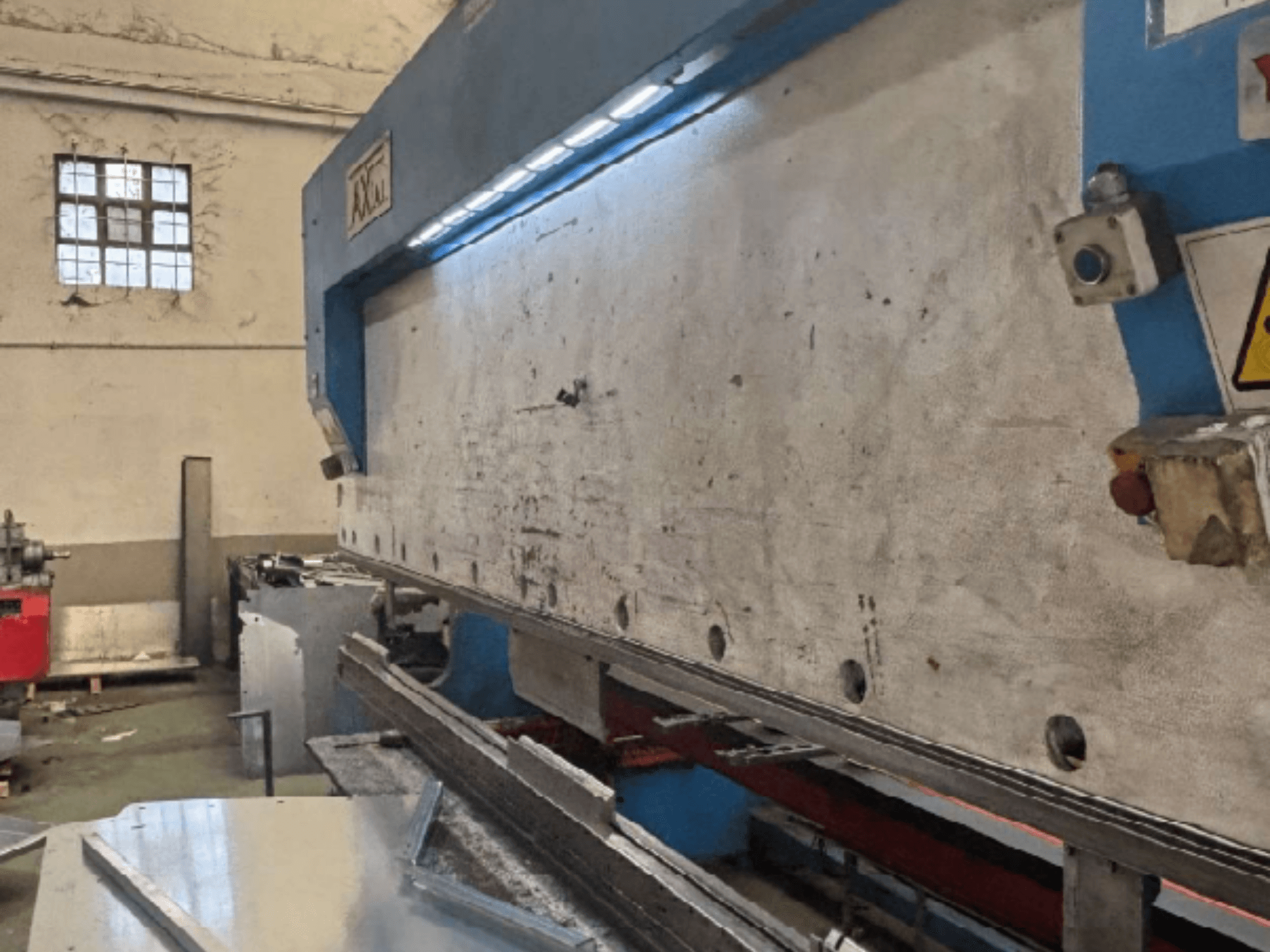 Axial PHS-W-124 raklapkezelő rendszer egy műhelyben, oldalnézet a munkafelület és a vezérlőpanel részleteivel.