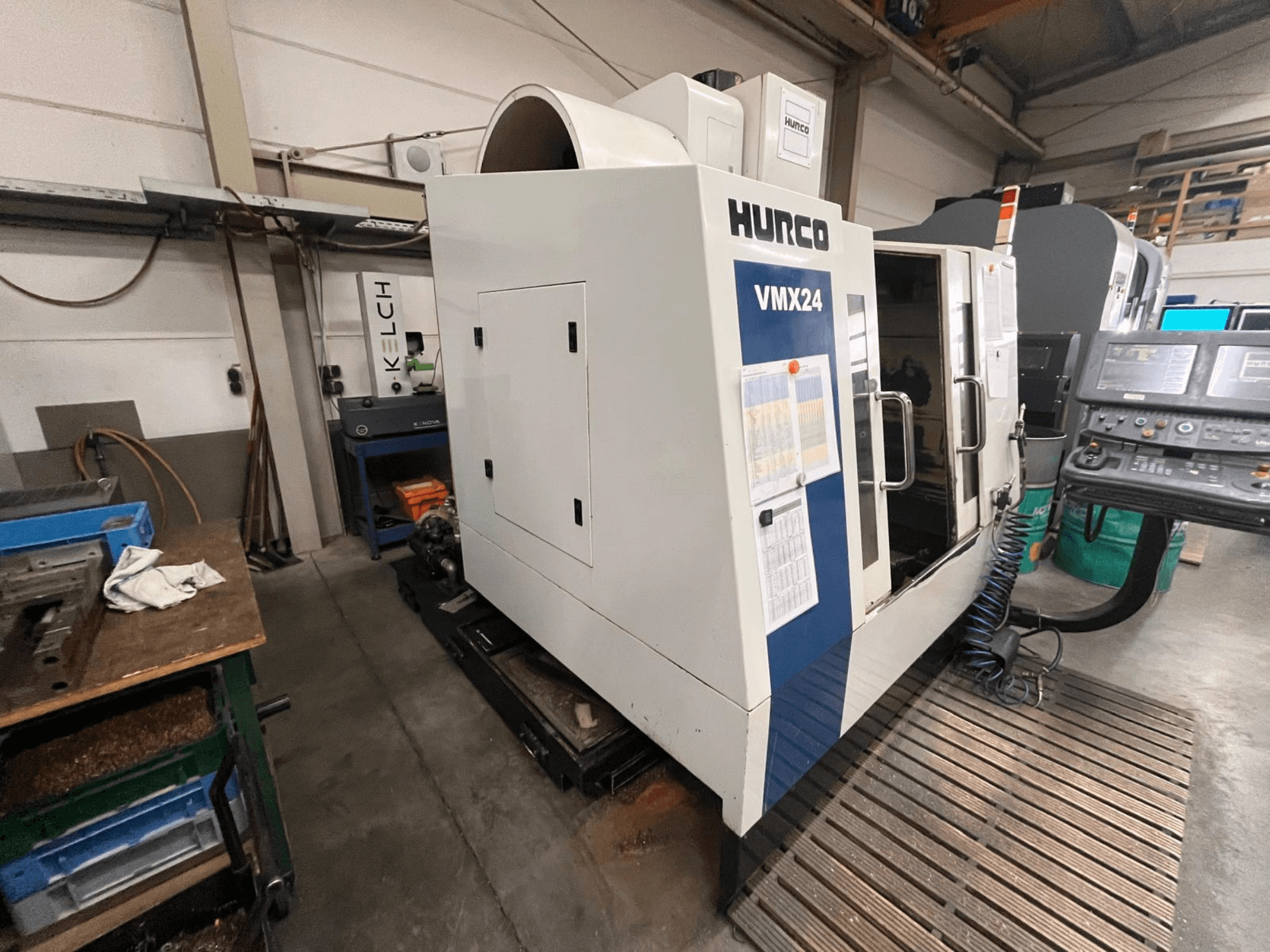 Hurco VMX24 CNC-gép egy műhelyben, elölnézetben; vezérlőpanel és nyitott bejárati ajtó.