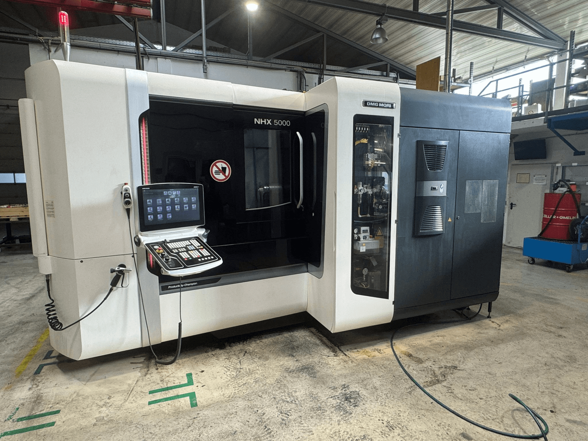 DMG MORI NHX 5000 vízszintes megmunkálóközpont, elölnézet a kezelőpanellel és a biztonsági jelzőkkel.