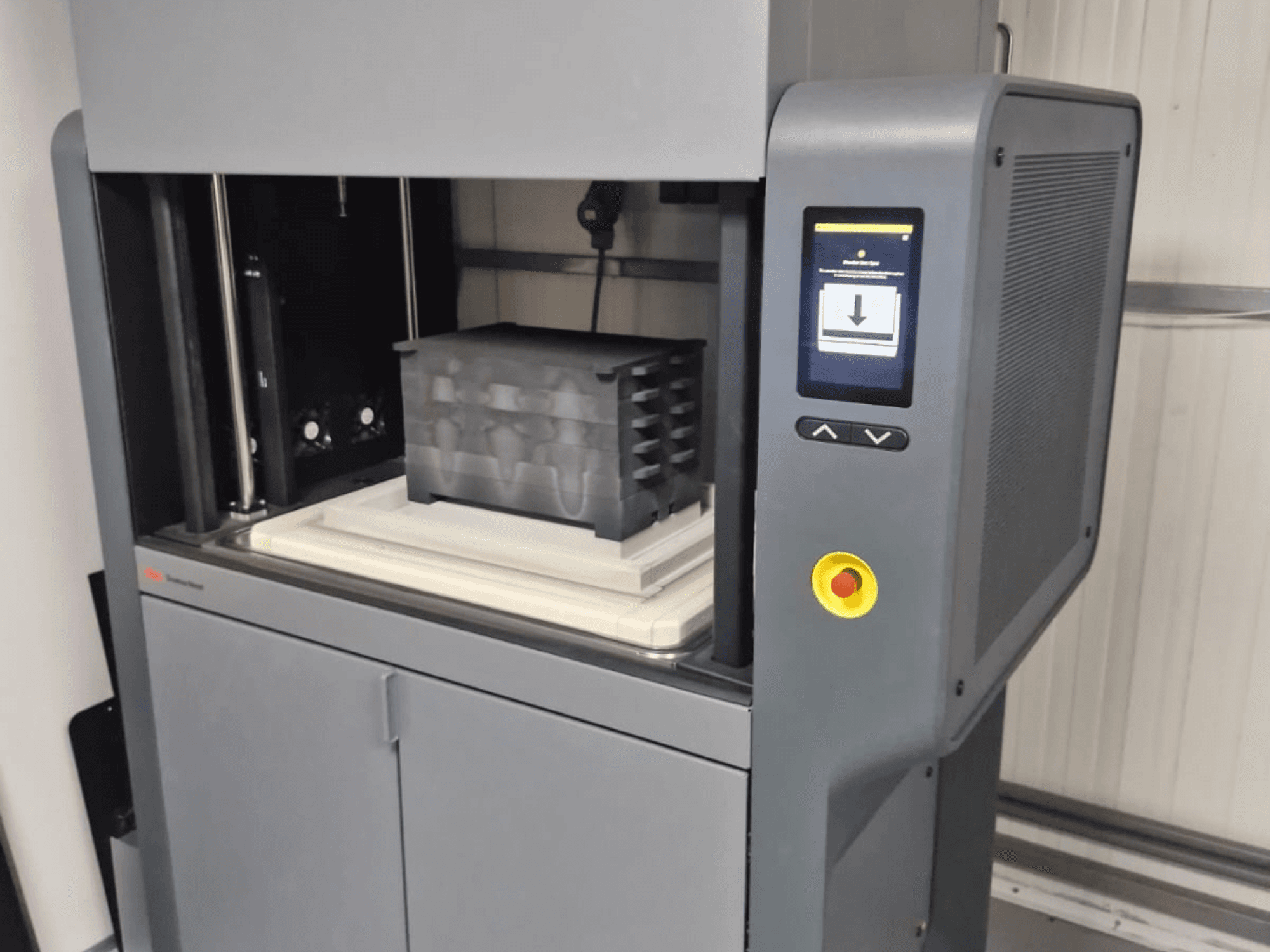 Metal Studio 2 3D nyomtató a Desktop Metal cégtől, elölnézetben a vezérlőpanel és a fekete tartályos nyomtatóágy.