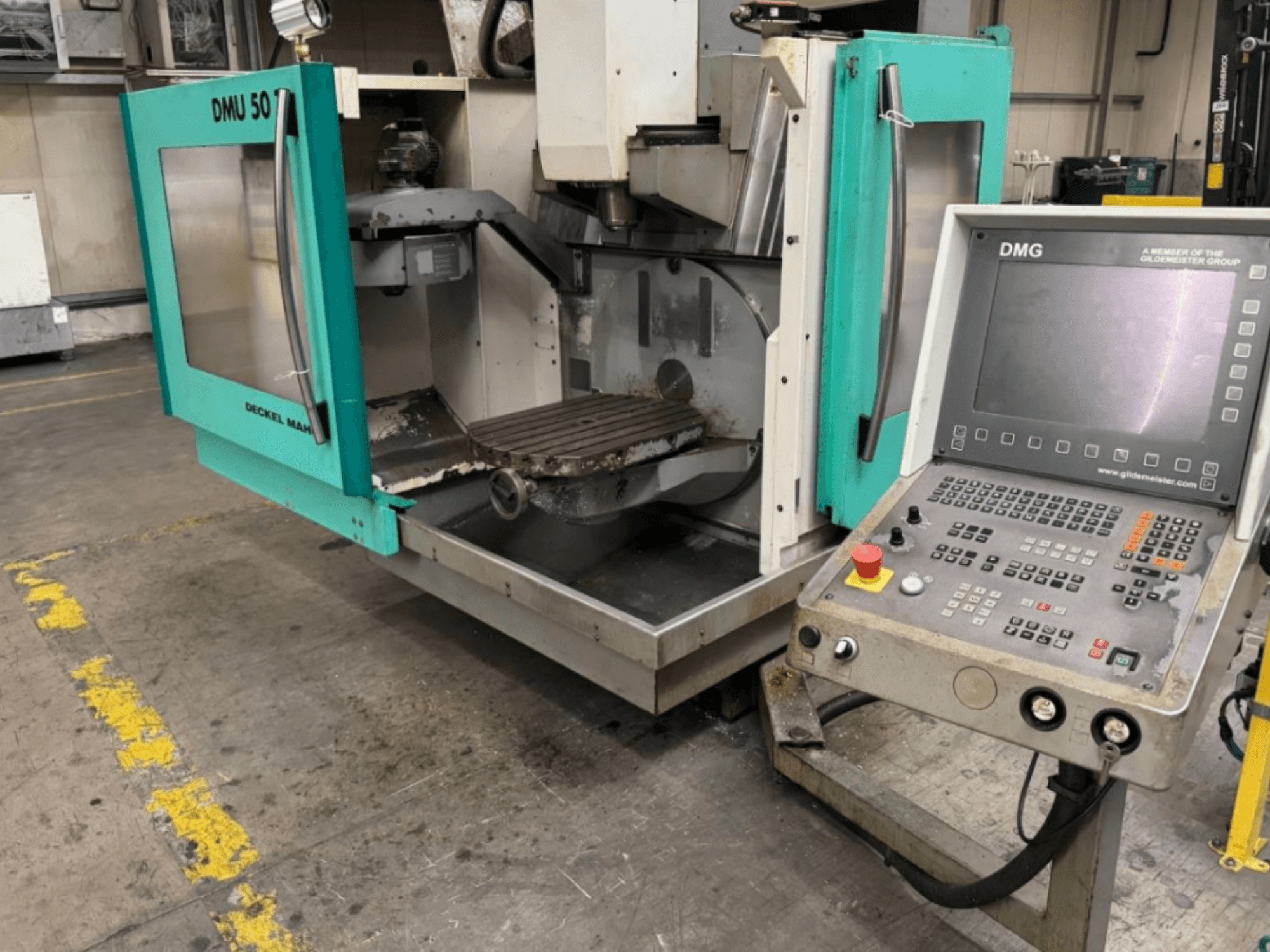 DMG DMU 50 marógép nyitott ajtókkal, a belső tér és a vezérlőpanel szemből nézve.