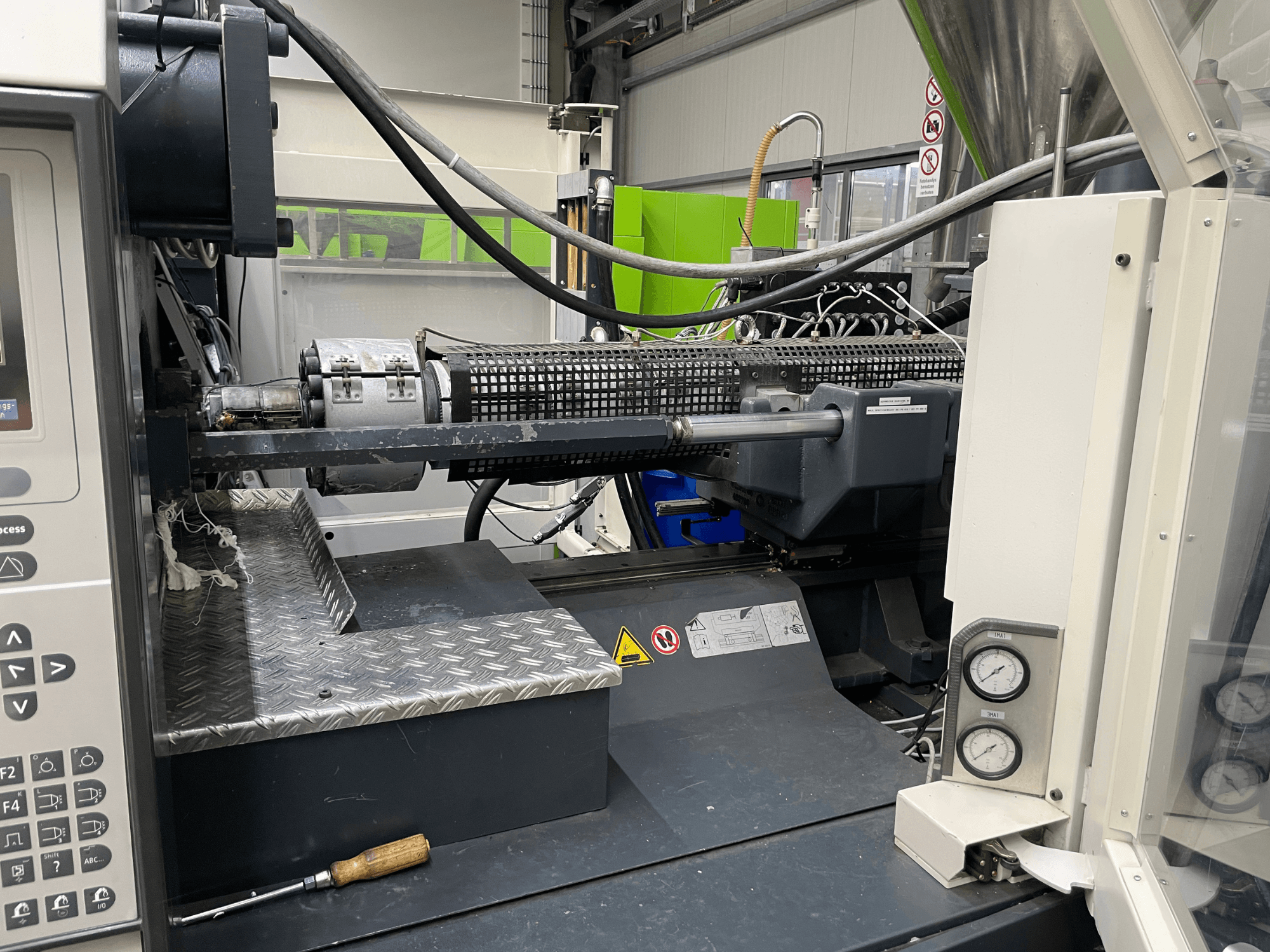 Fröccsöntőgép oldalnézet a vezérlőpanel, az extruder és a nyomásmérők láthatóak, ideális a gyártási feladatokhoz.