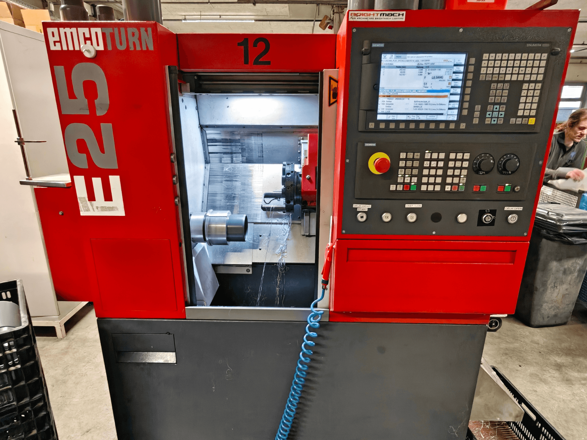EMCO TURN E25 gép elülső nézete, a vezérlőpanel, a szerszámtartó és a belső terület a vágószerszámmal látható.