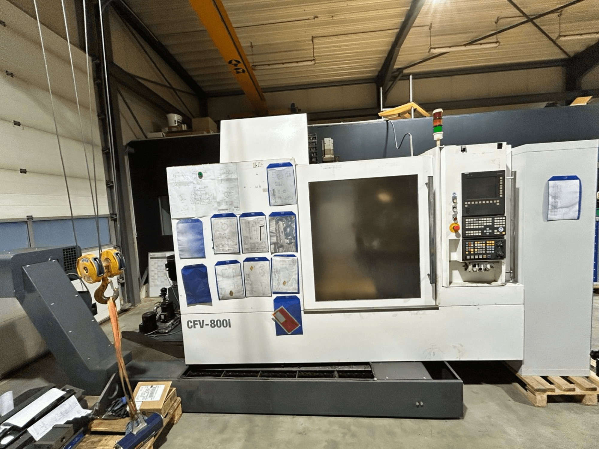 A CFV-800i CNC-gép elölnézetben, vezérlőpanellel, oldalsó dokumentumokkal és daruval gyári beállításban.