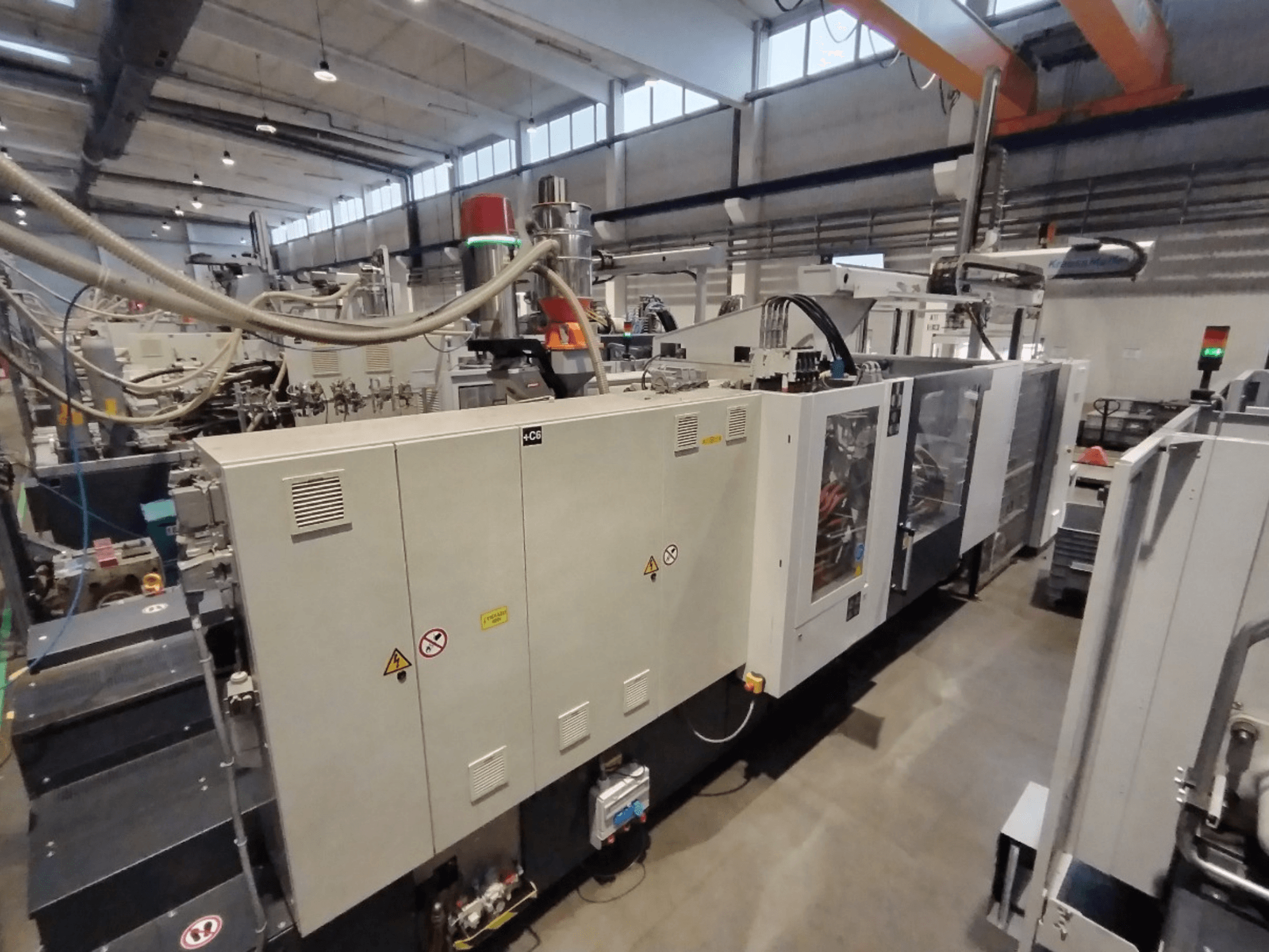 Ipari fröccsöntőgép oldalnézetből, vezérlőpanellel és biztonsági figyelmeztetésekkel. Márkanév: B: Ismeretlen.