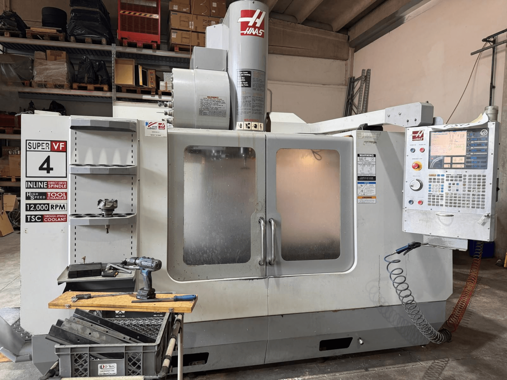 A HAAS VF-4SSHE függőleges megmunkáló központ elölnézete a vezérlőegységgel, a szerszámtartóval és a 12 000 fordulat/perc sebességű orsóval; nagy sebességű, precíziós gép.