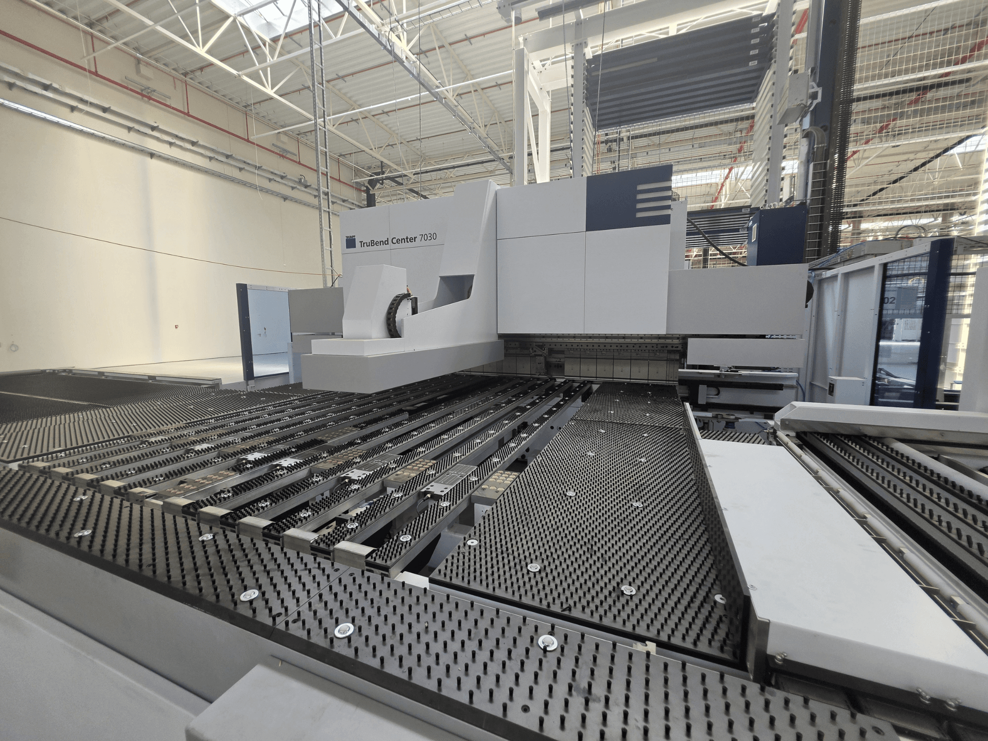 A TRUMPF TruBend Center 7030 hajlítógép gyári környezetben, elölnézetből, amelyen látható a bonyolult felépítésű munkaasztal és a hajlítókar.
