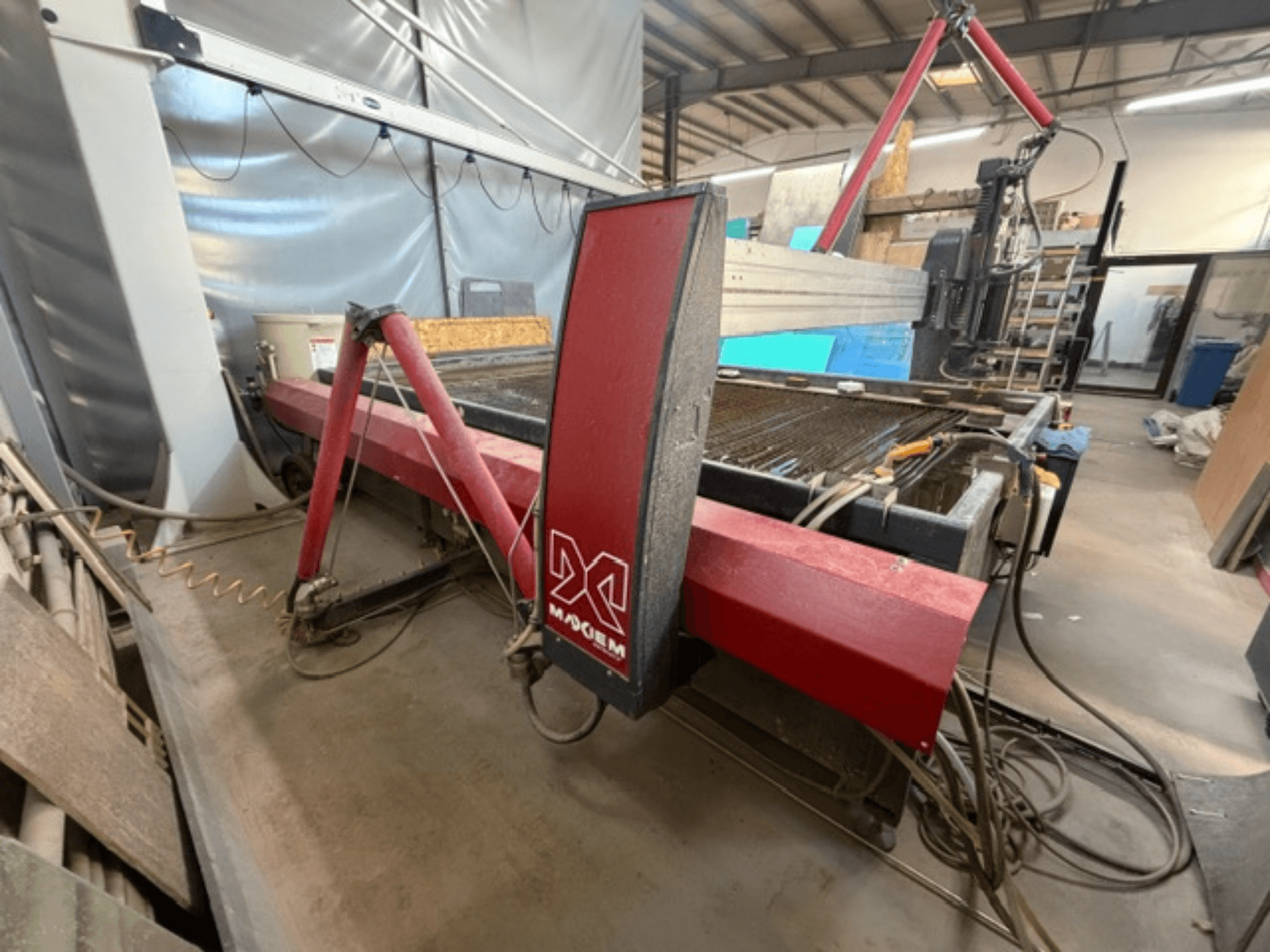 Vörös vízsugaras vágógép az X márkától, oldalnézetből, a mechanikai alkatrészek és a csővezetékek részleteivel.