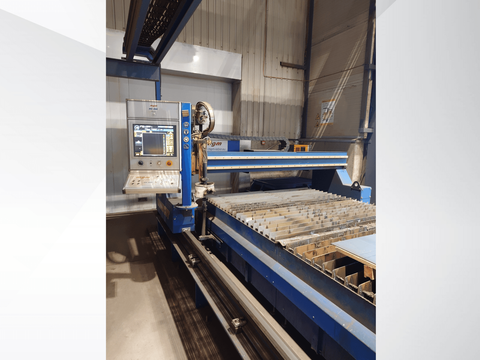 A PlasmaCam CNC-vágógép, elölnézetben a vezérlőpanel és a fémvágó ágy lécekkel.