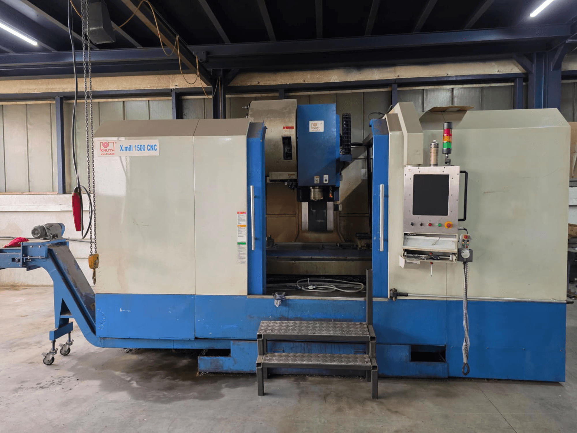 KNUTH X-MILL 1500 CNC függőleges megmunkáló központ, oldalnézet, amelyen látható a vezérlőpanel, a lépcsők és a kimeneti szállítószalag.