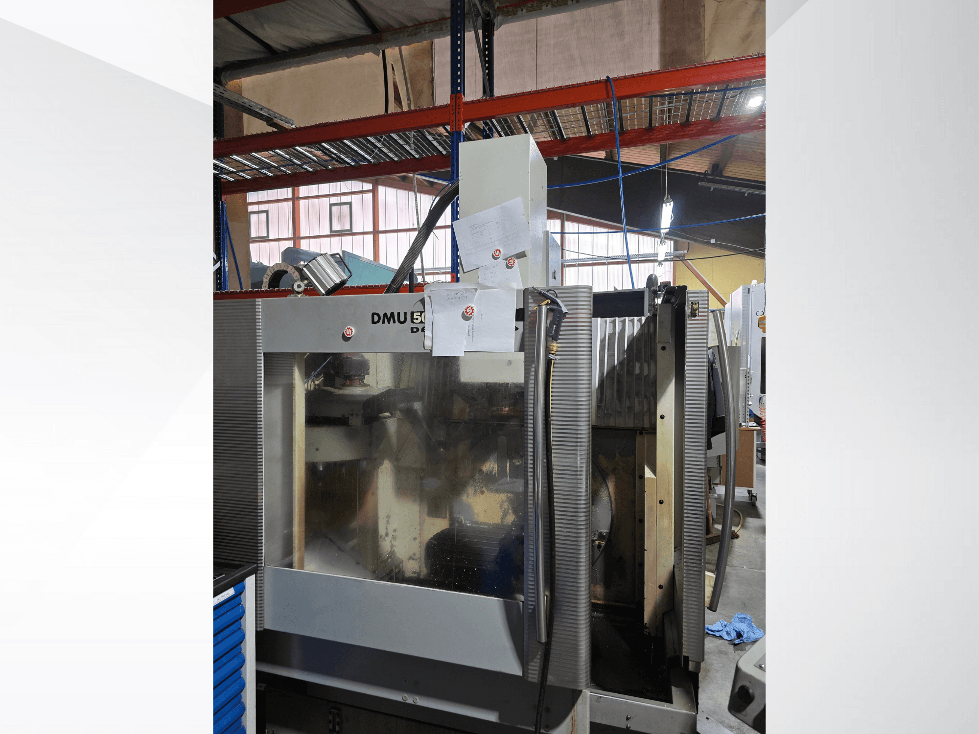 DMU 50 3 tengelyes CNC megmunkálóközpont egy műhelyben, szemből, a működő alkatrészek és a csatolt dokumentumok megjelenítésével.