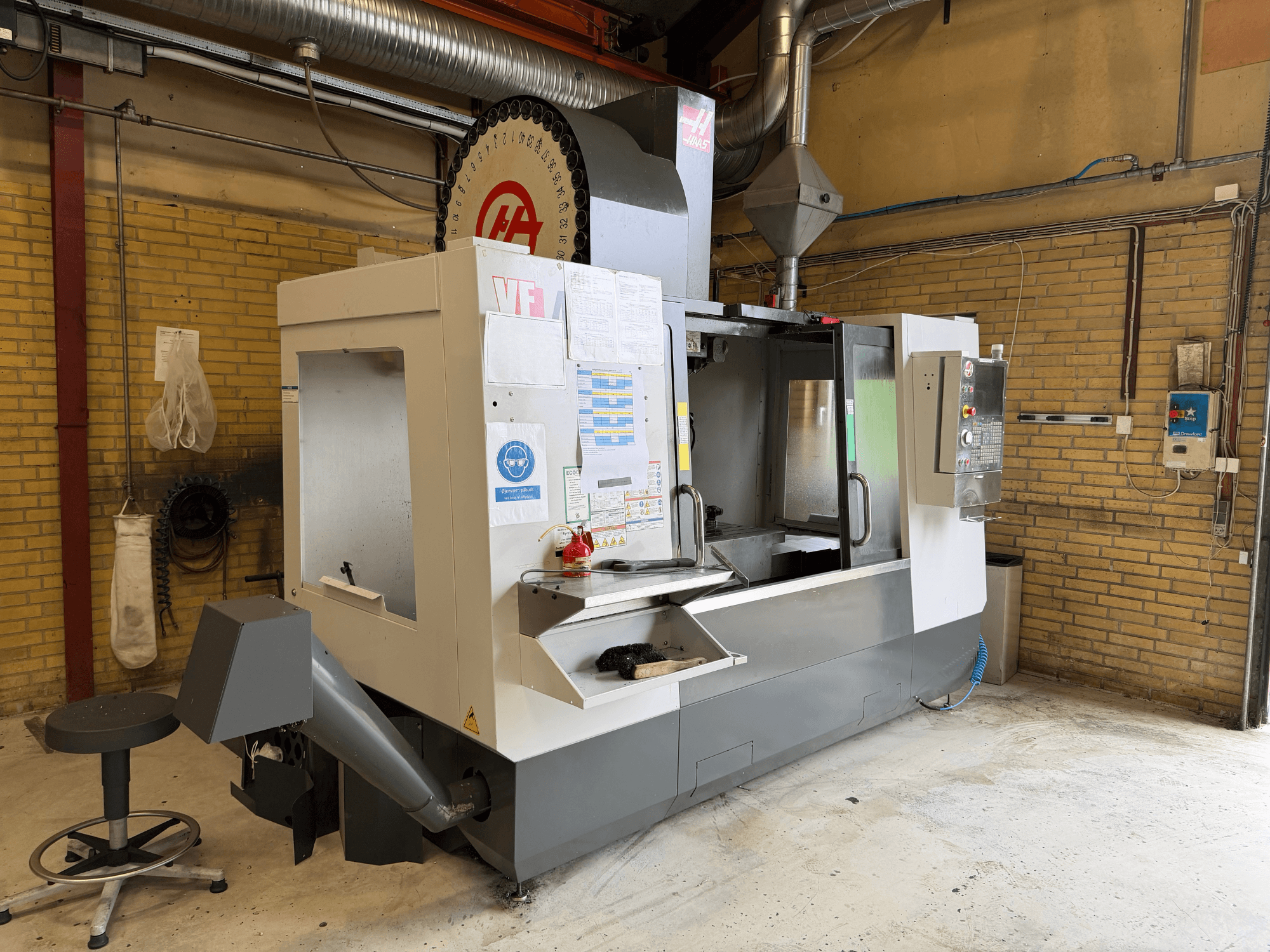 HAAS VF-4 függőleges megmunkáló központ, elölnézet; a képen látható a vezérlőpanel, a szerszámtartó, valamint a háttérben a gyártási beállítás.