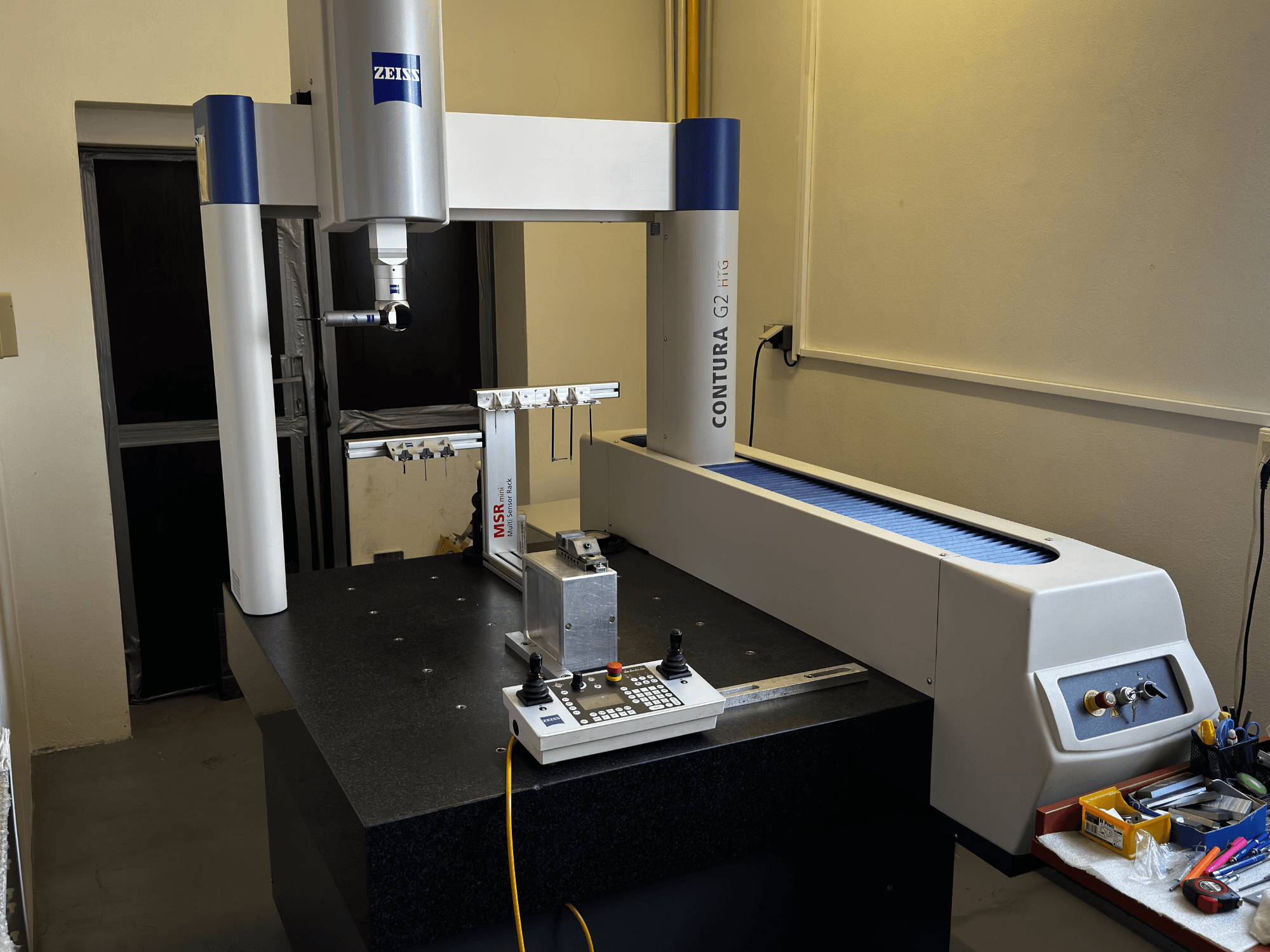 ZEISS Contura G2 CMM laboratóriumi környezetben, elölnézetben a mérőkar, a vezérlőpanel és a szomszédos munkaterület.