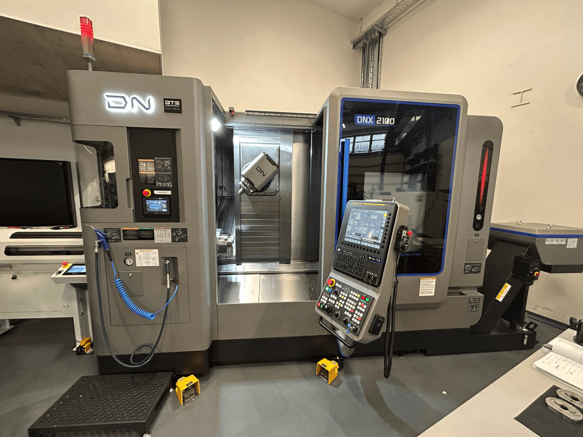 DN ONX 2100 CNC gép, előlnézet, vezérlőpanel, munkaterület és szerszám. Biztonsági lámpával és működésjelzőkkel felszerelve.