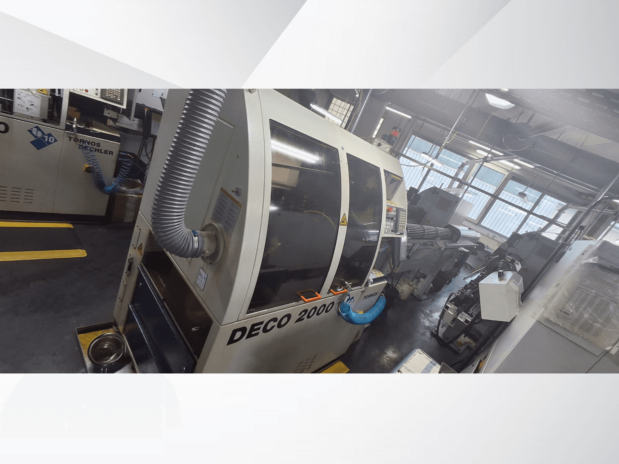 DECO 2000 CNC gép műhelyben, elölnézetben, szellőzőcsővel és vezérlőpanellel, precíziós megmunkálásra tervezve.