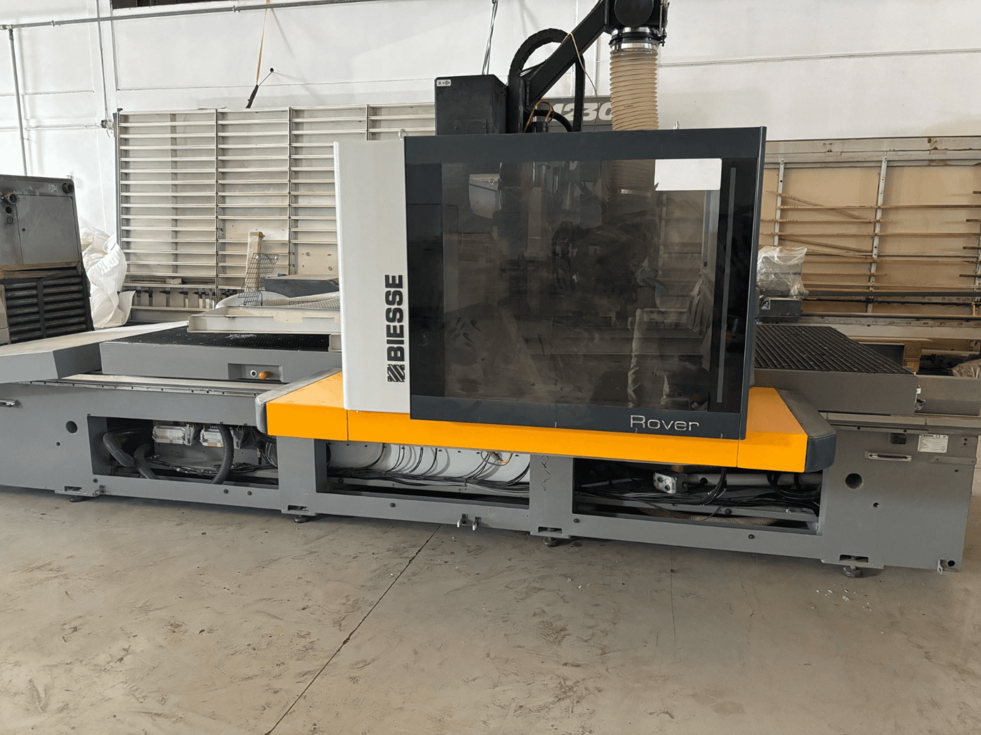 Biesse Rover CNC megmunkálóközpont, előlnézet, nagyméretű vezérlőpanel, sárga ékezetek és látható mechanikus alkatrészek.