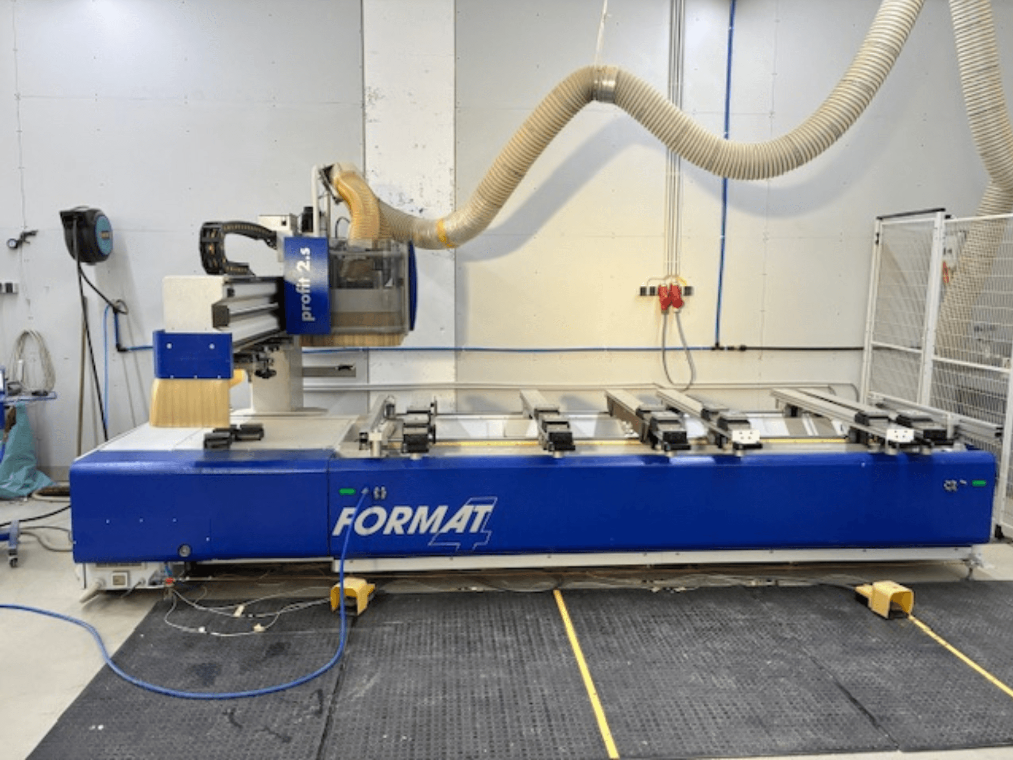Kék FORMAT 4 CNC router, Profit 2.5 modell, oldalnézetben a vágási terület és a porelszívó rendszer, gumiszőnyegen.